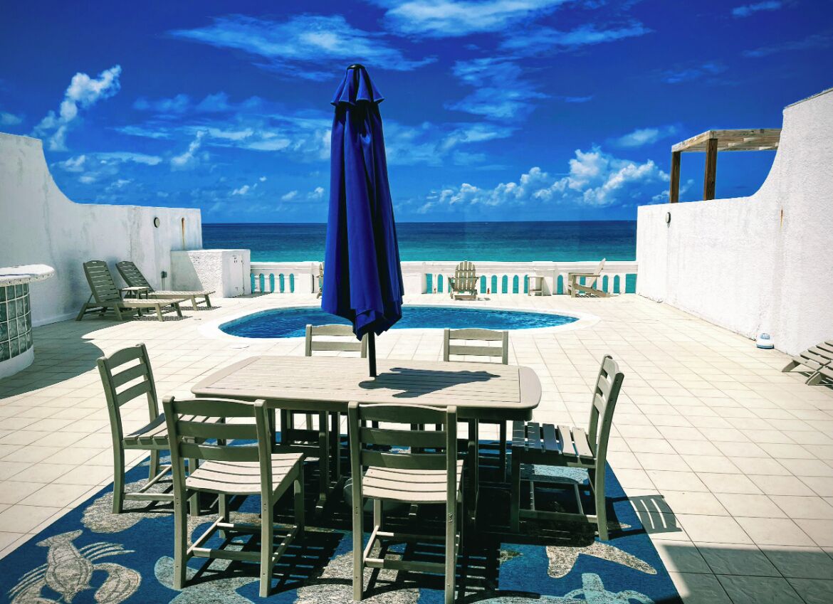 The pool deck with a dining table and a view of the sea.
