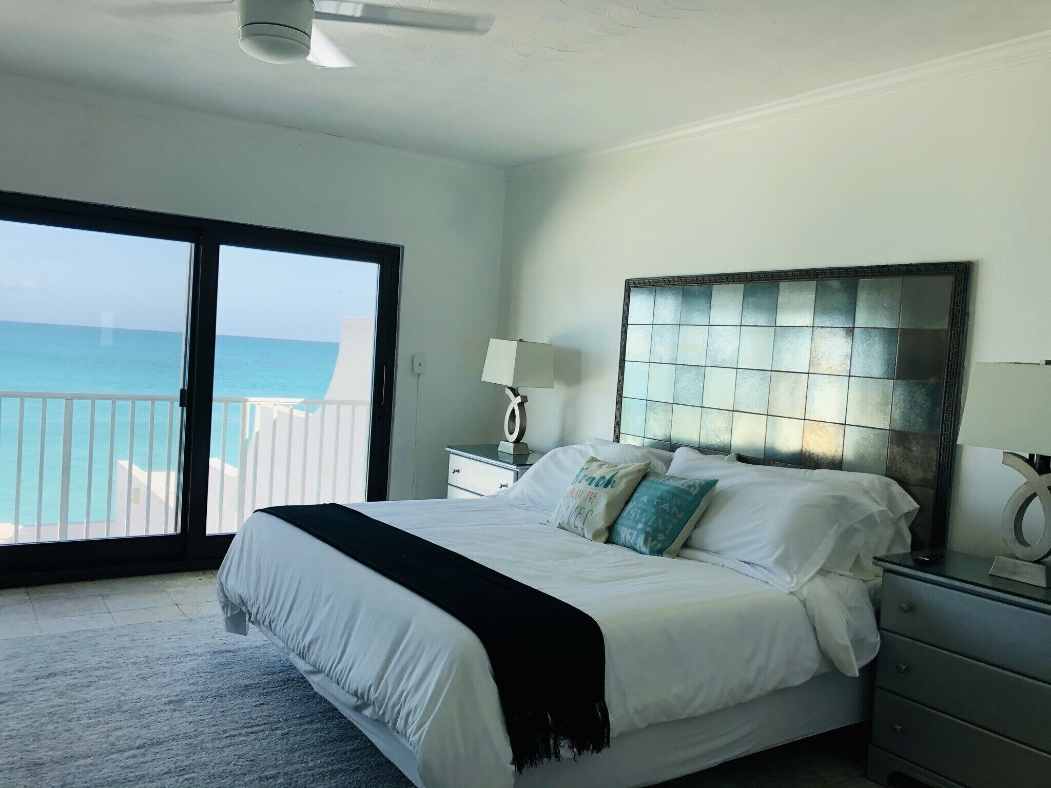 A bedroom with a tiled headboard and a door to the balcony.