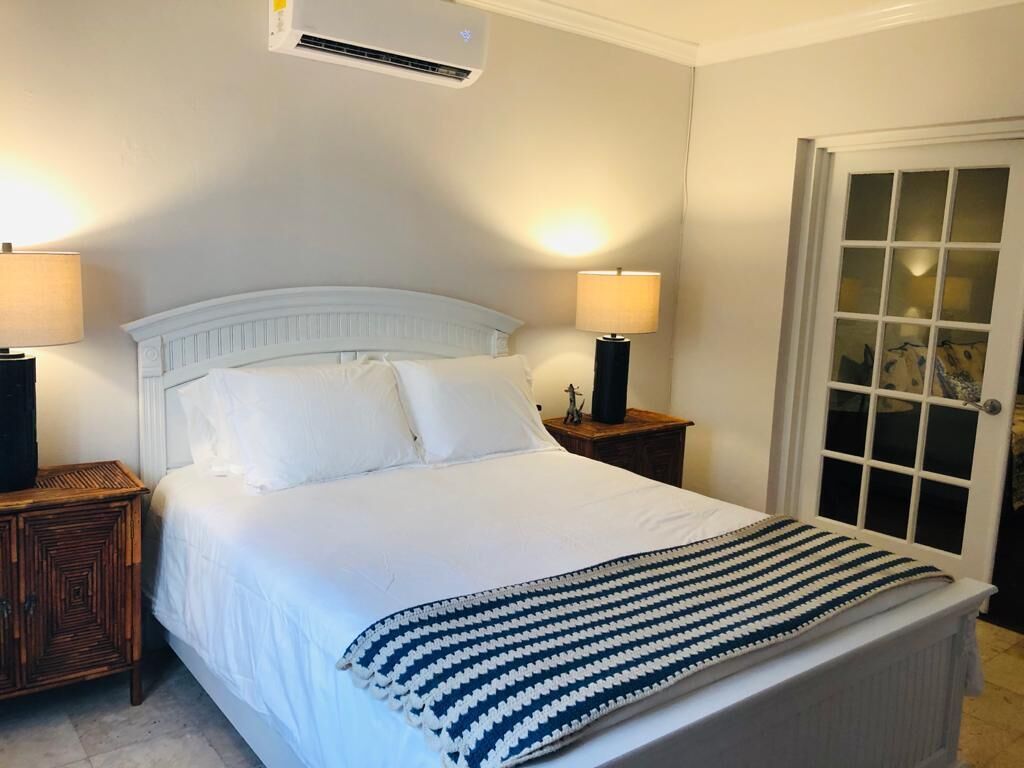 A bedroom with a white headboard and a striped throw.