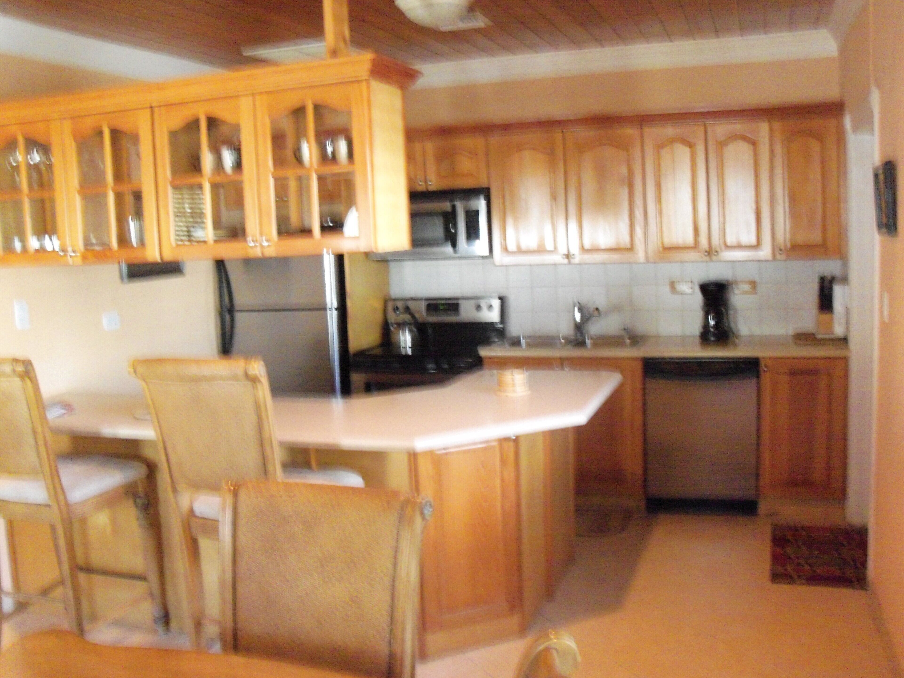 The kitchen has wood cabinets, a refrigerator, a stove, and a breakfast bar.