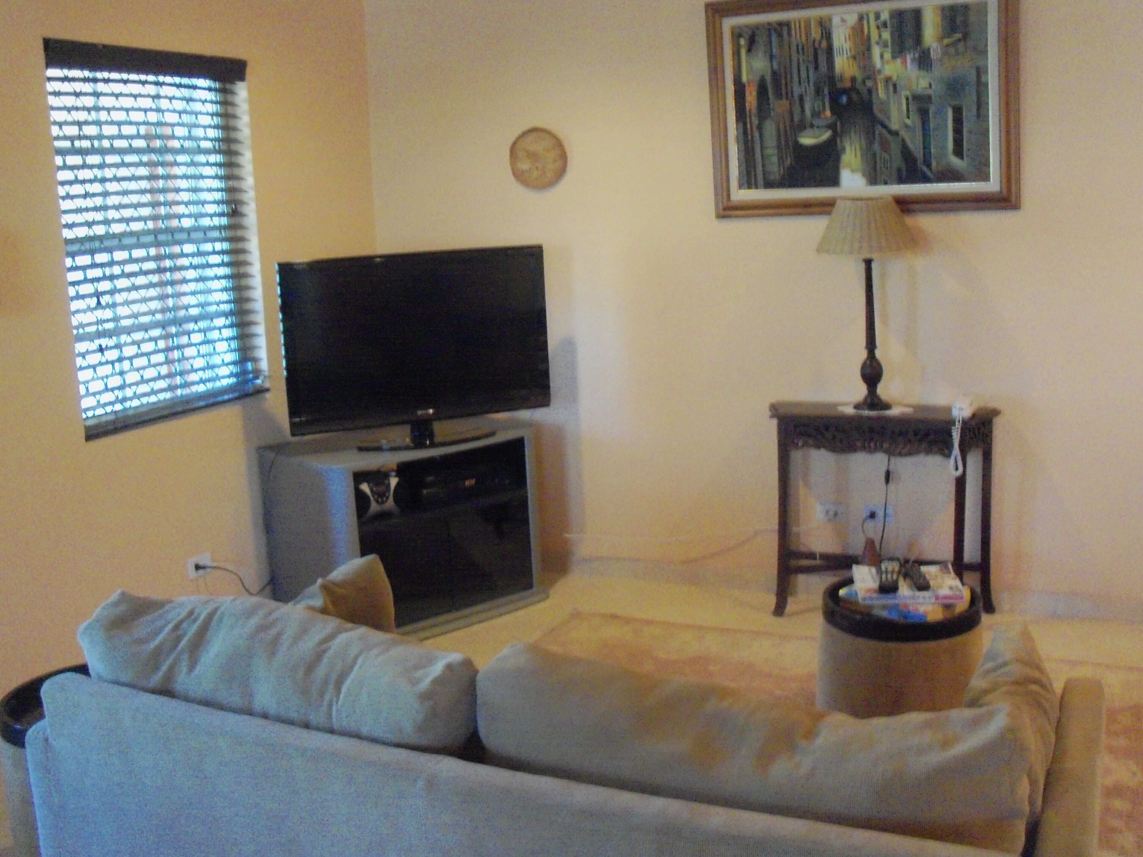 The living room has a sofa, a television, and a side table with a lamp.
