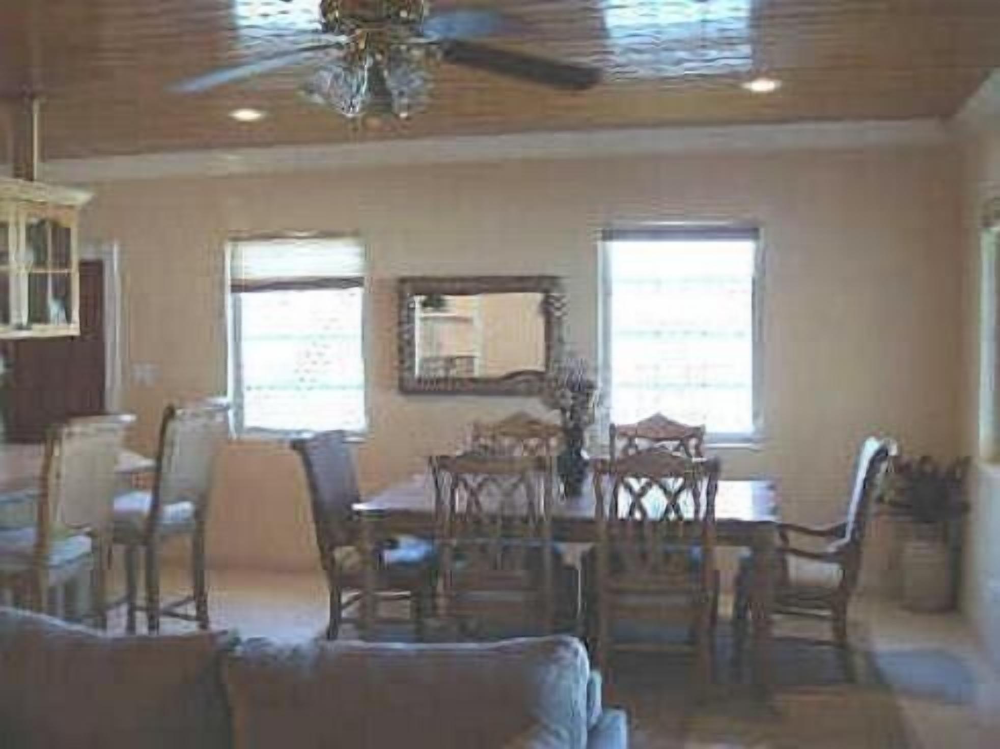 The dining room has a table with chairs and a ceiling fan.