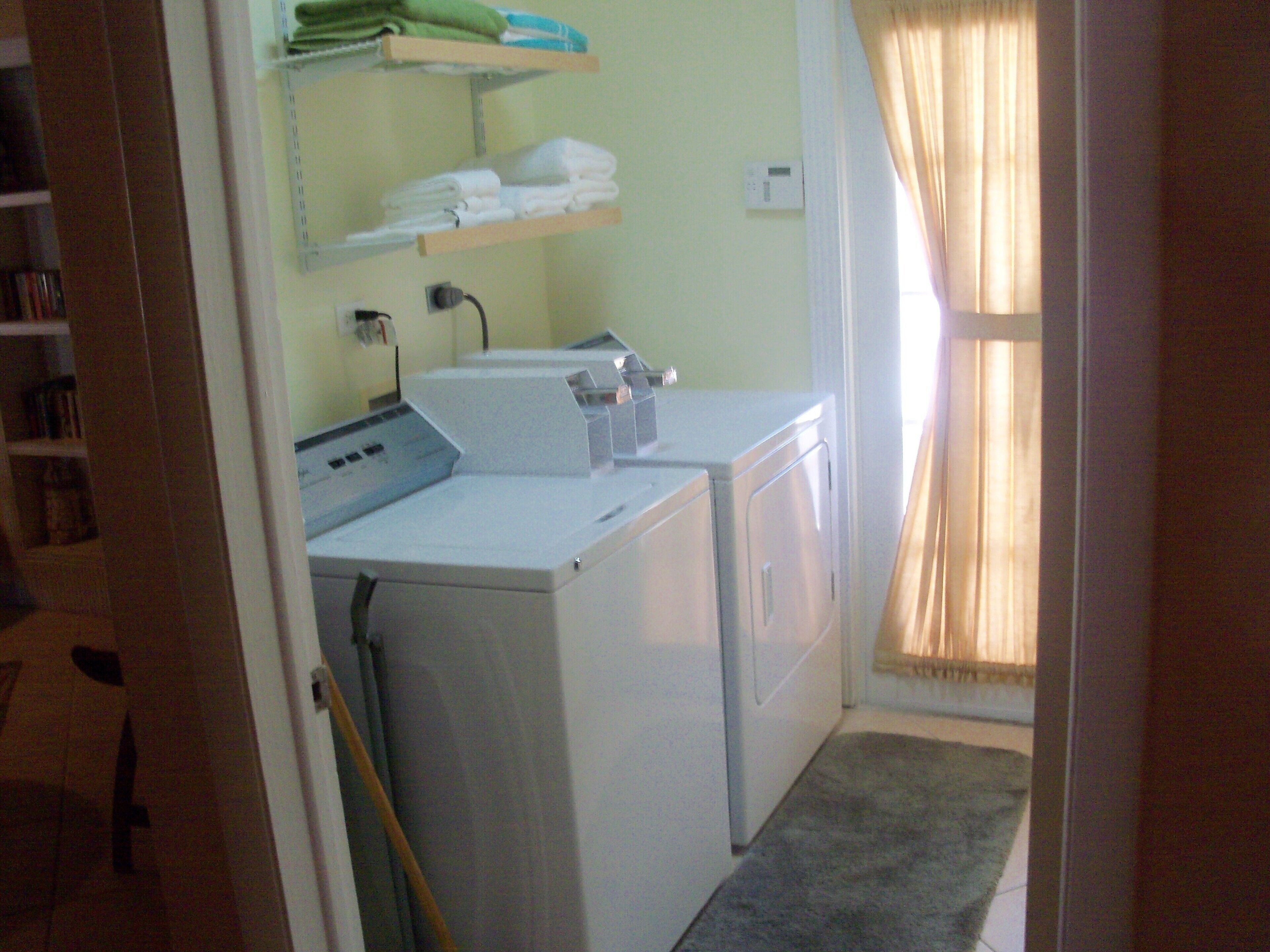 The laundry room has a washer, a dryer, and shelves with towels.