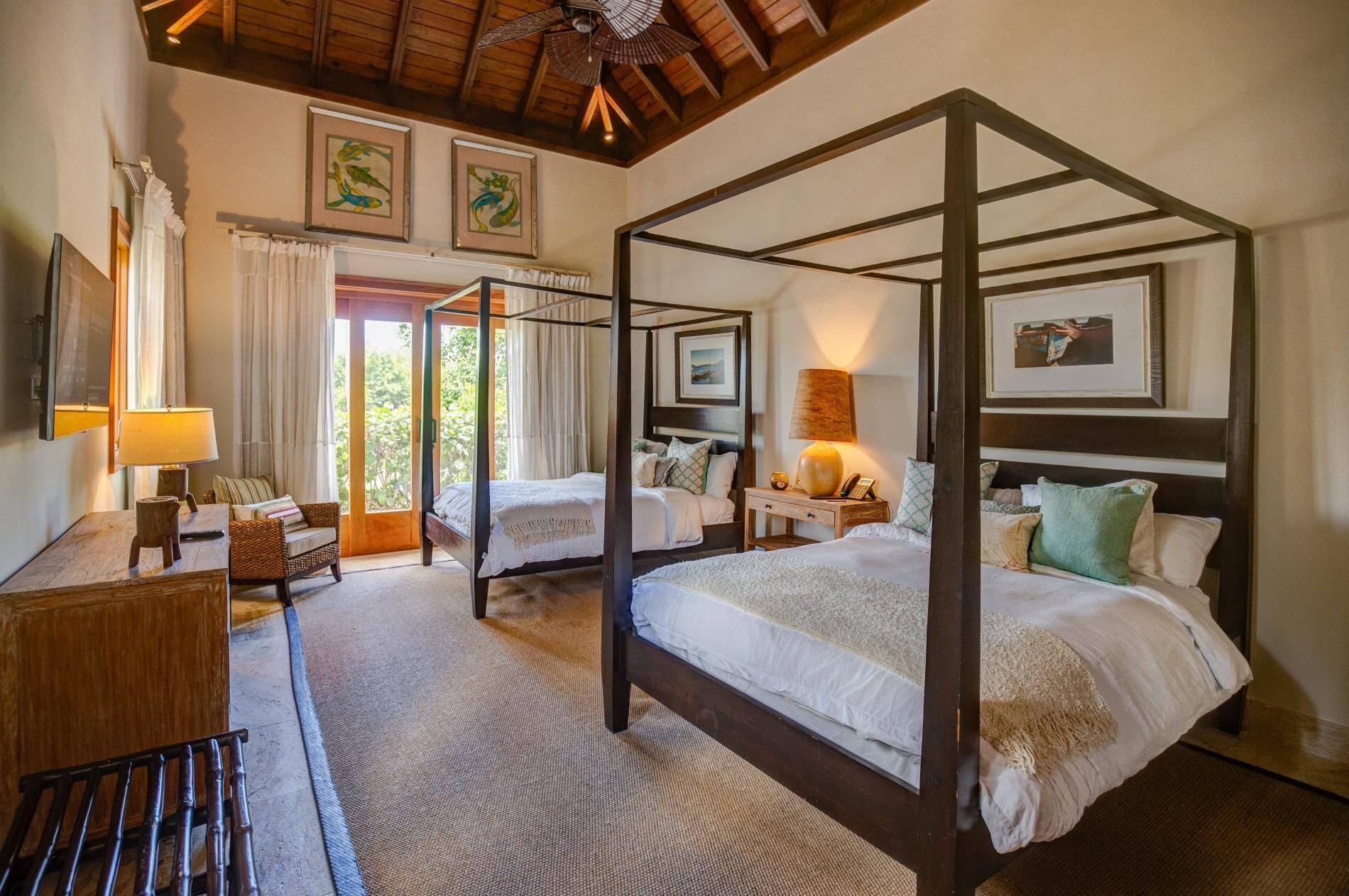 A bedroom with two four-poster beds and a ceiling fan.