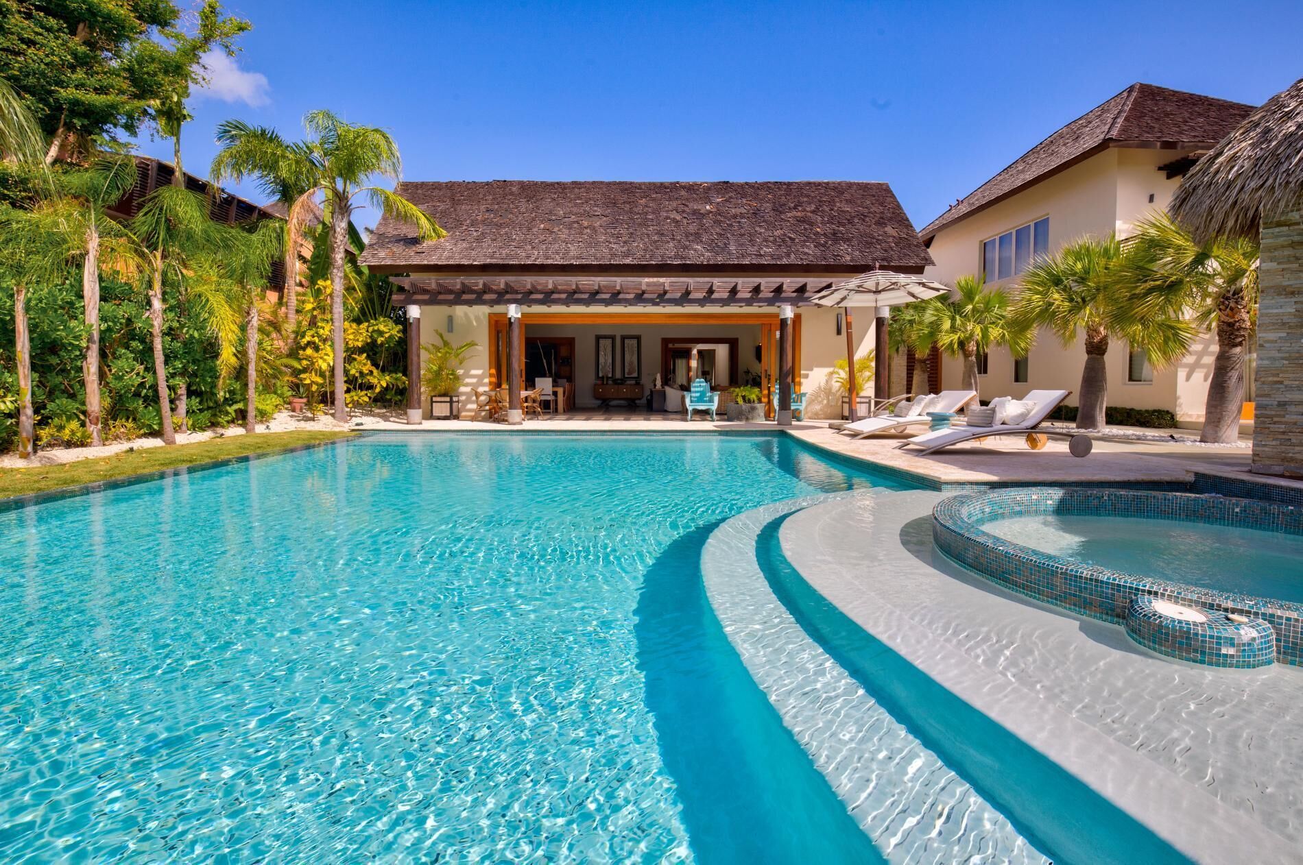 The private pool with wide steps and the hot tub in front of the covered terrace.