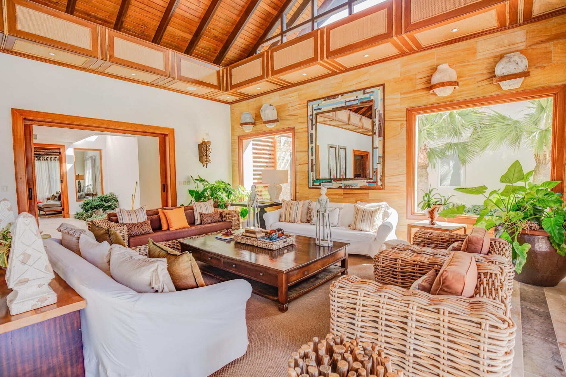 A living room with sofas, wicker armchairs, and a high wood ceiling.