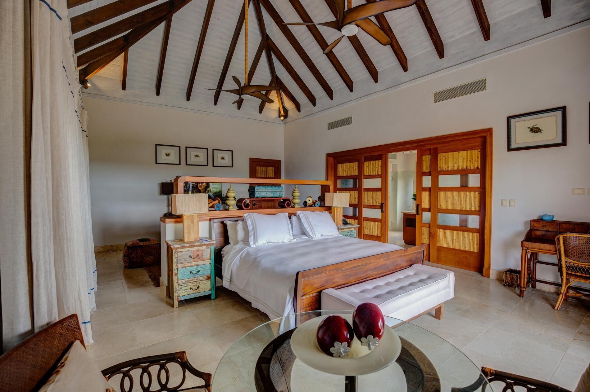 A bedroom with a large bed and ceiling fans.