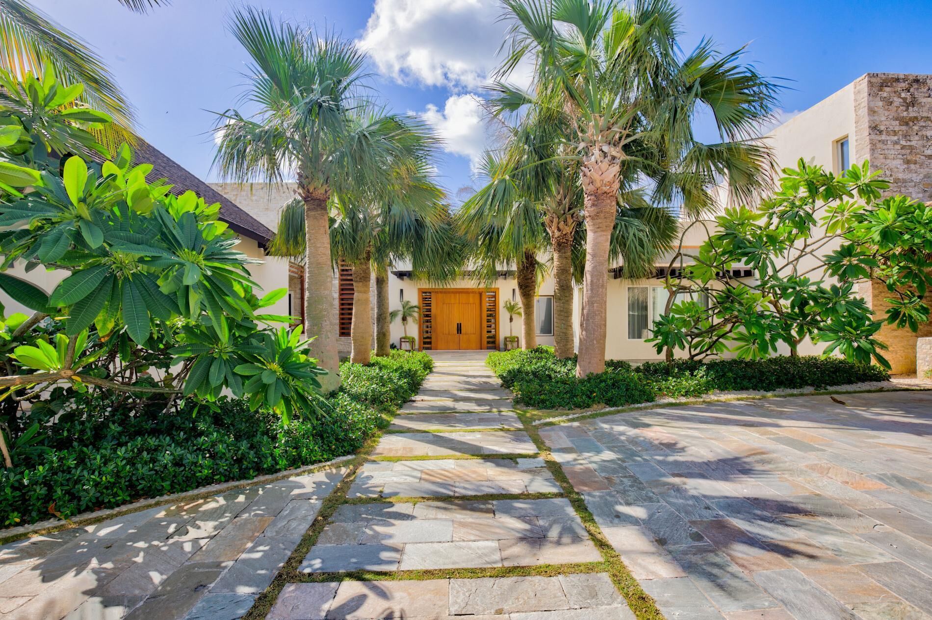 The entrance of the villa with a wood double door and palm trees.
