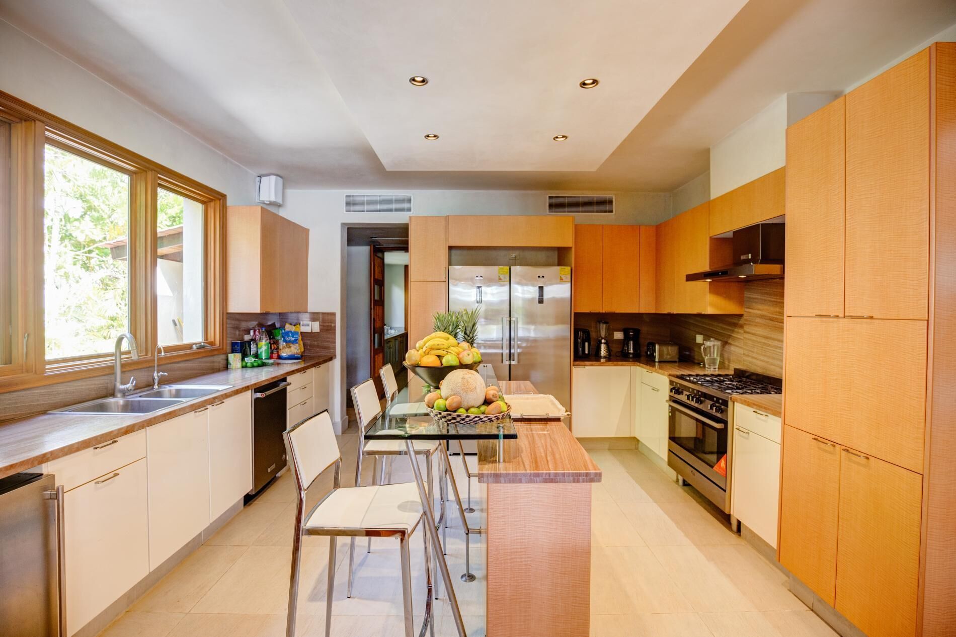 The kitchen with two refrigerators, a gas range, and a glass table.