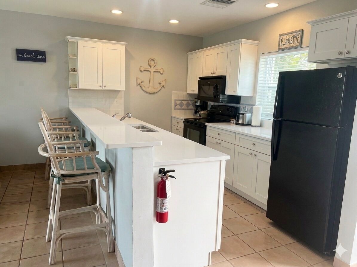 A kitchen with white cabinets and a black refrigerator.