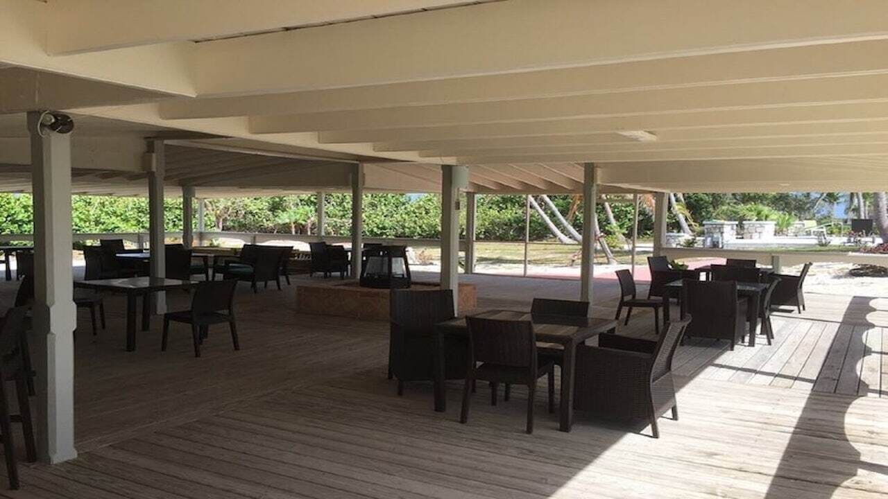 A covered deck with tables and chairs.