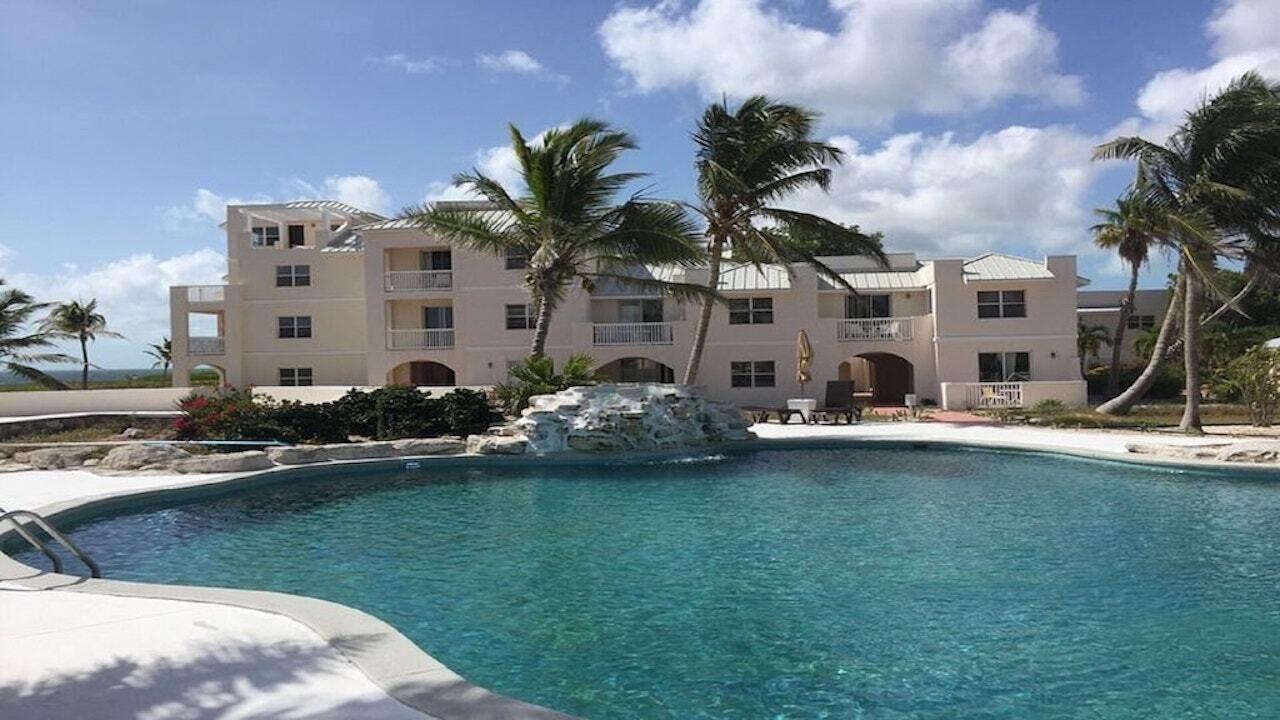 The pool with a rock waterfall in front of a three-story building.