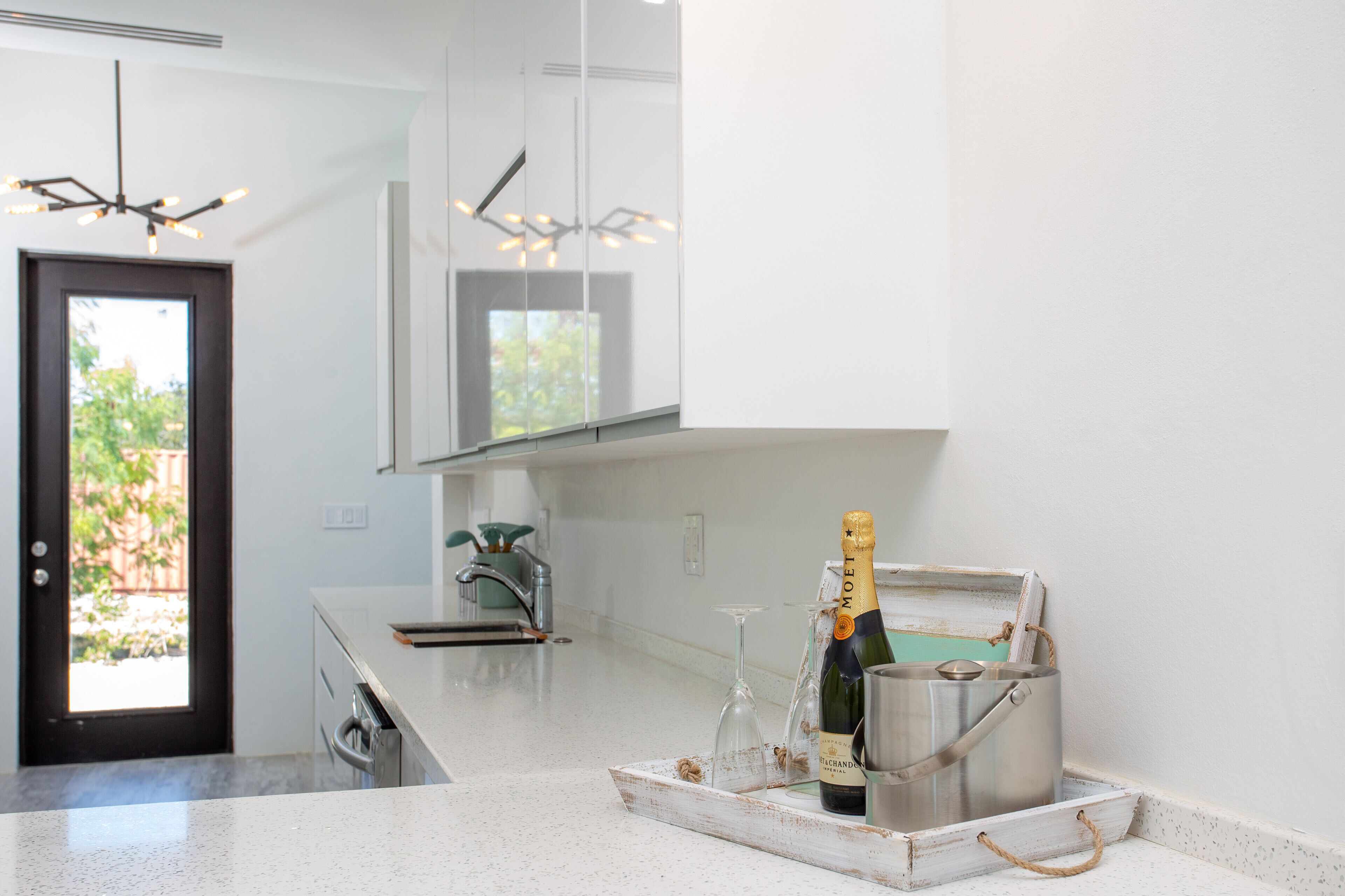 A kitchen counter with a tray, two glasses, a bottle, and an ice bucket.