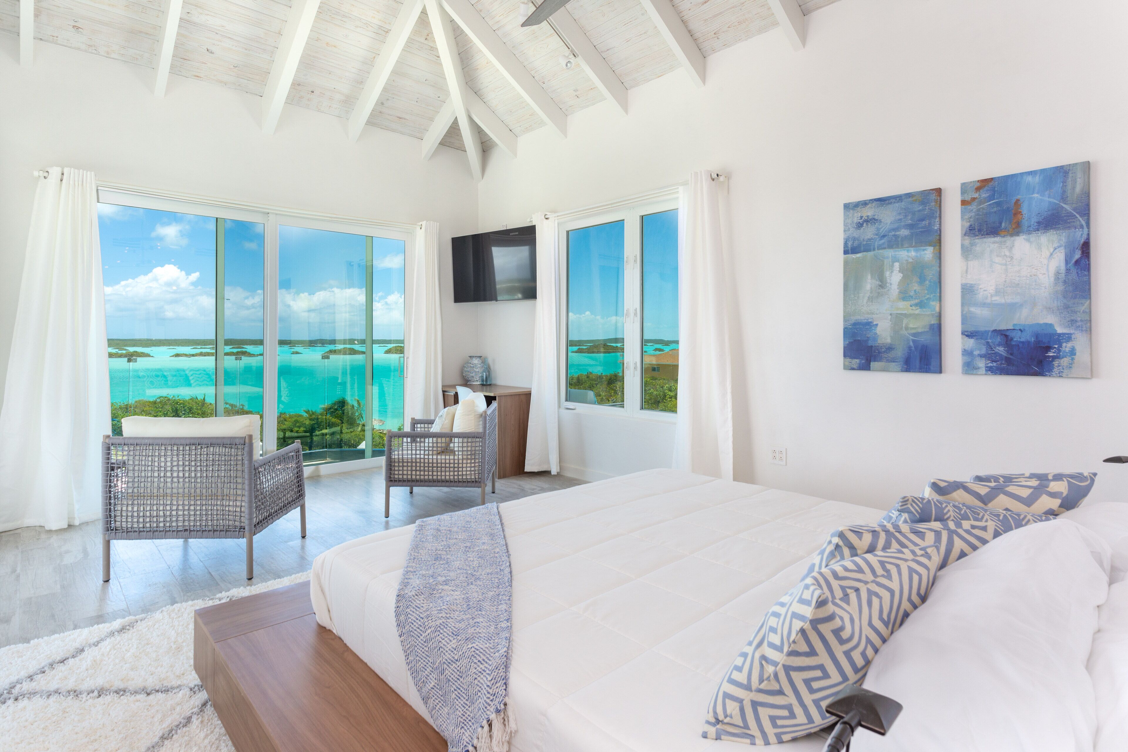 A bedroom with two chairs and a view of the Chalk Sound lagoon.