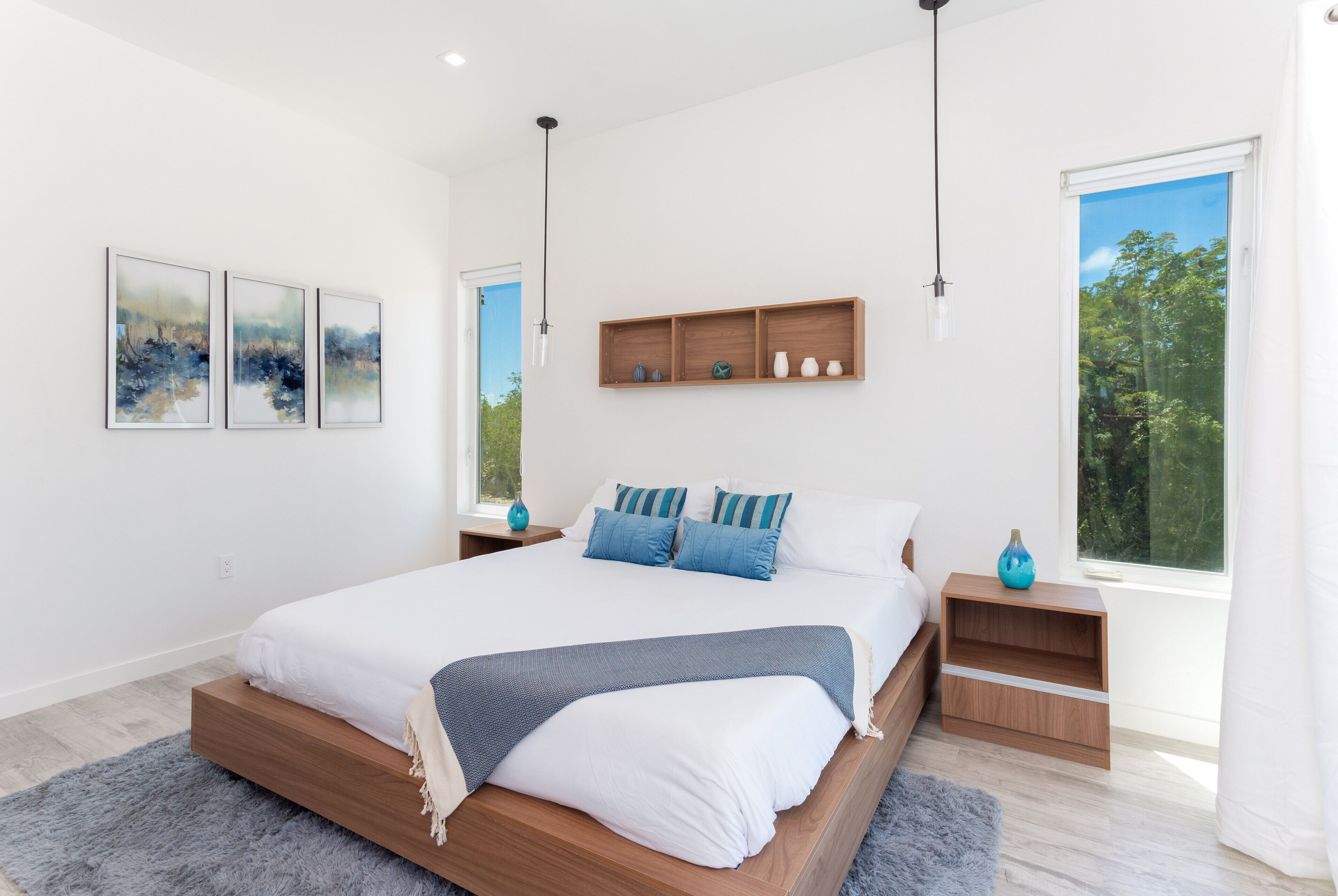 A bedroom with a wood bed, blue pillows, and three pictures on the wall.