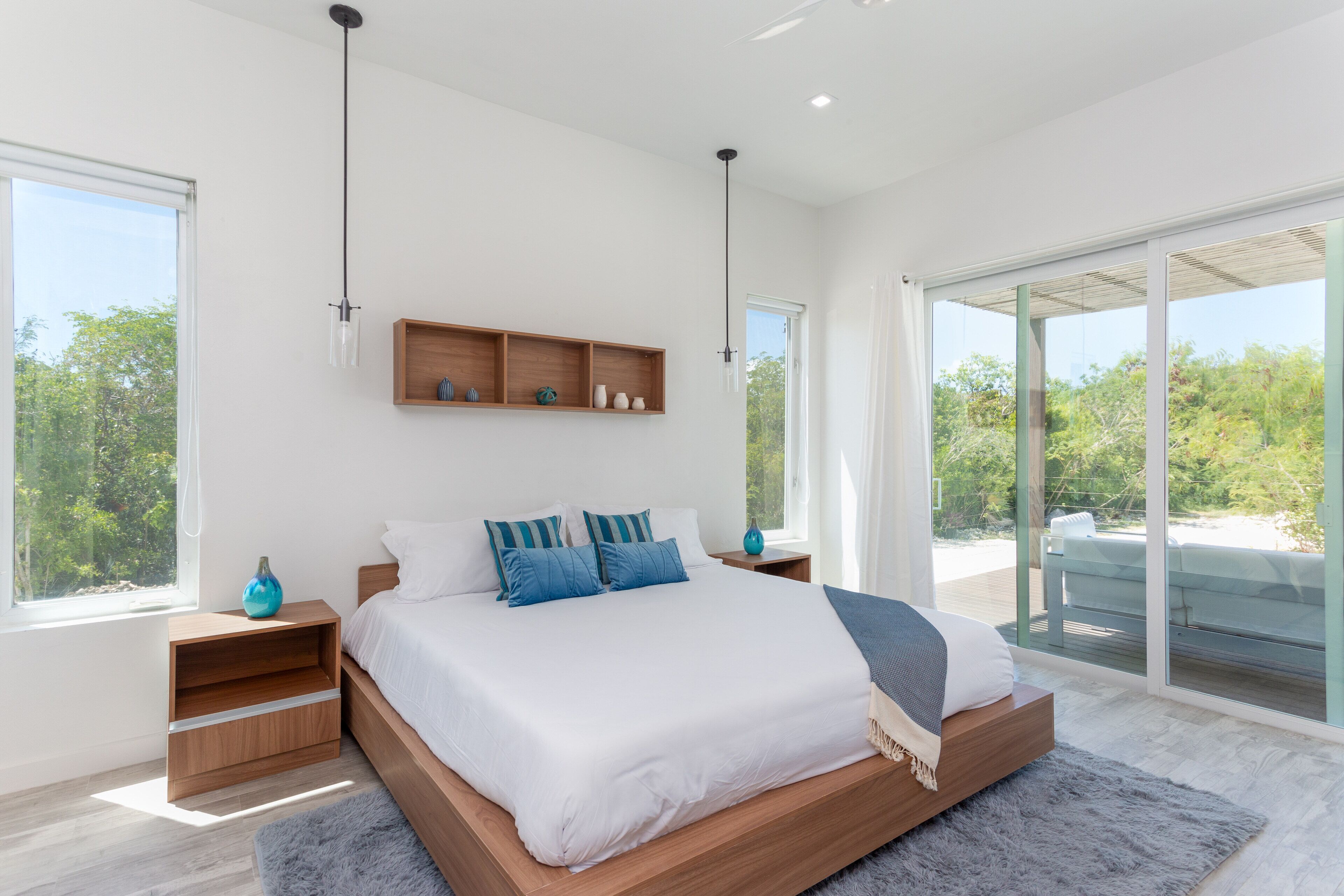 A bedroom with a wood bed, a shelf above it, and a glass door to the terrace.