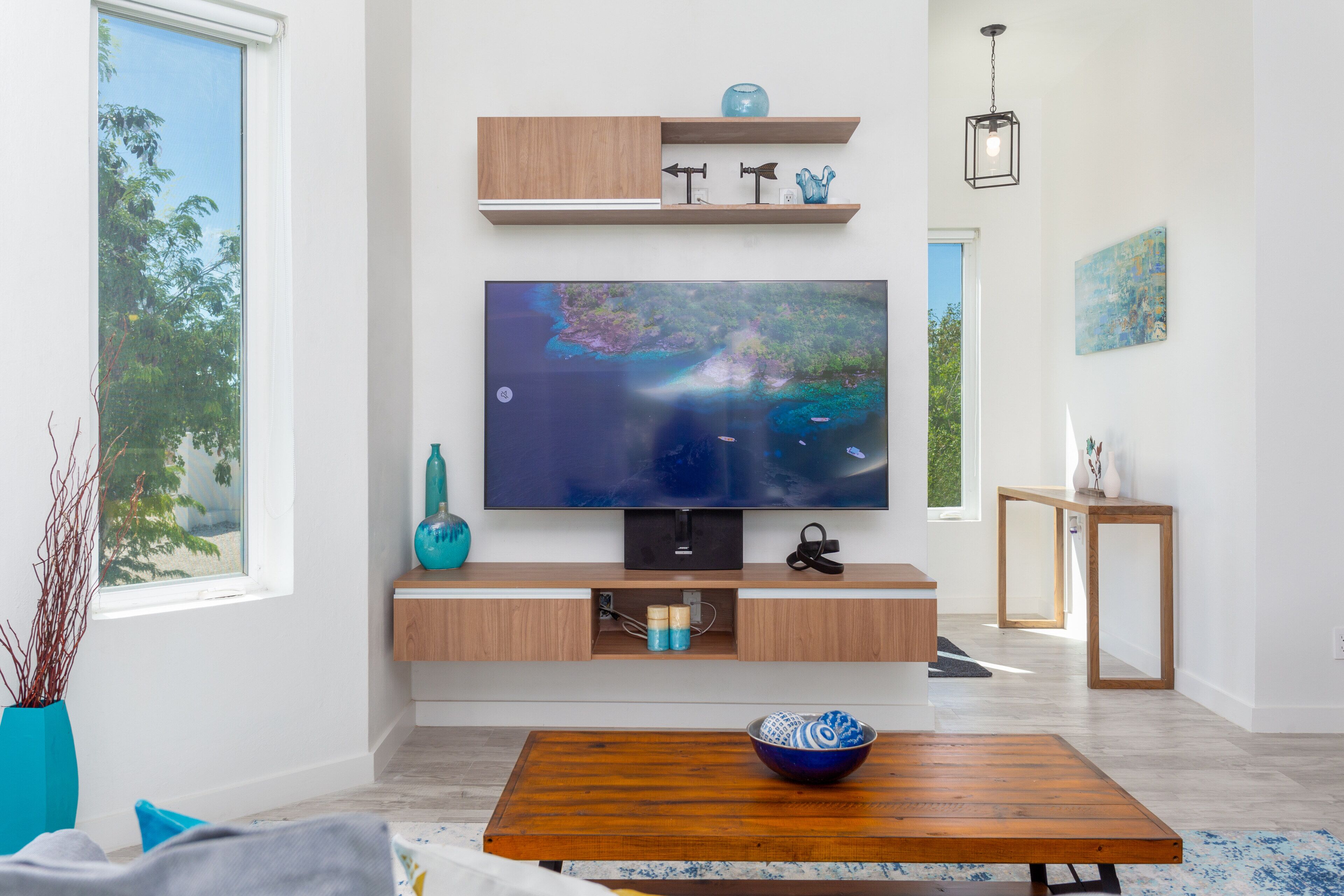 A television on a wall with wood shelves and a low wood cabinet.