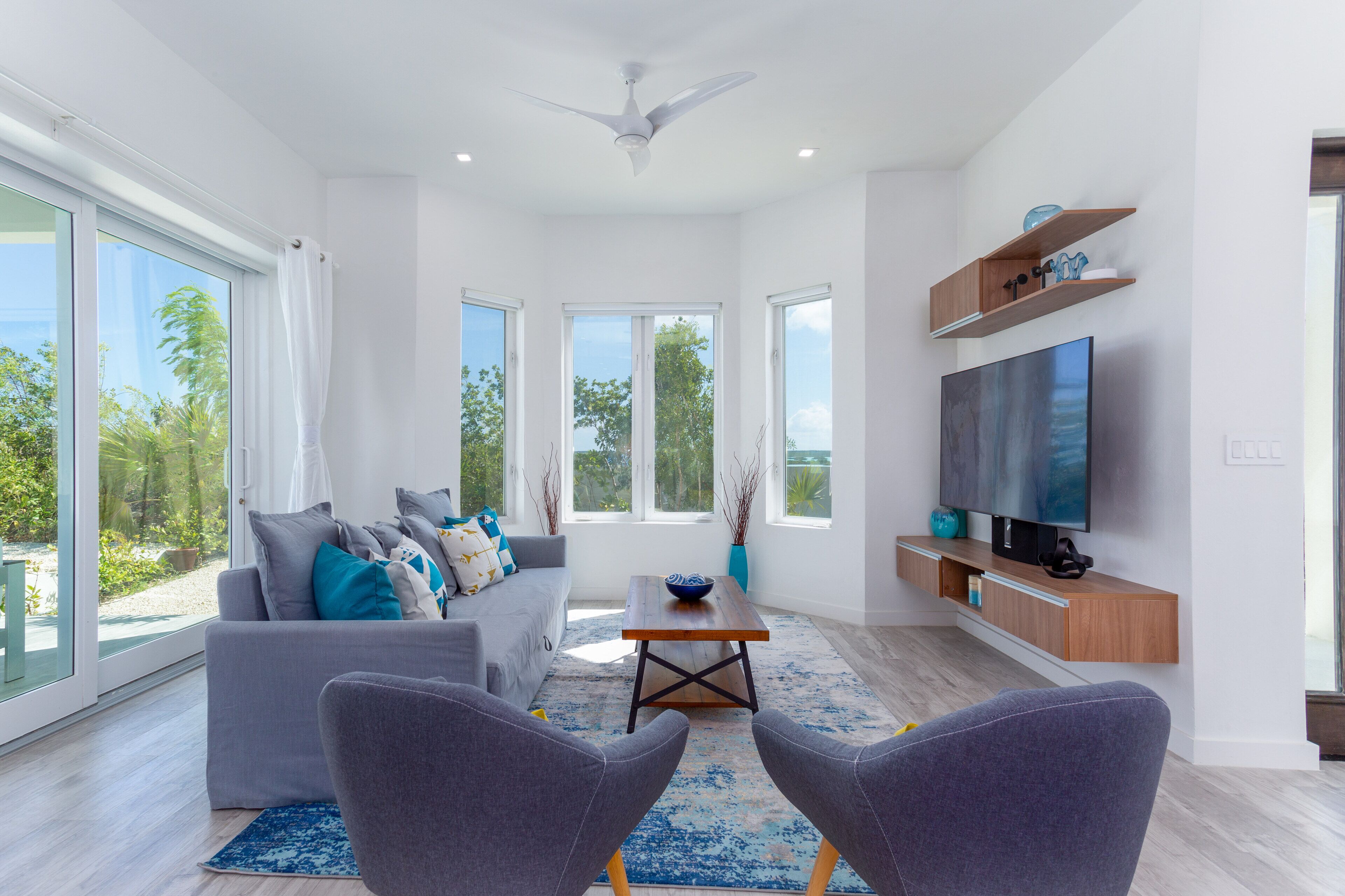 A living room with a gray sofa, two armchairs, and a television.