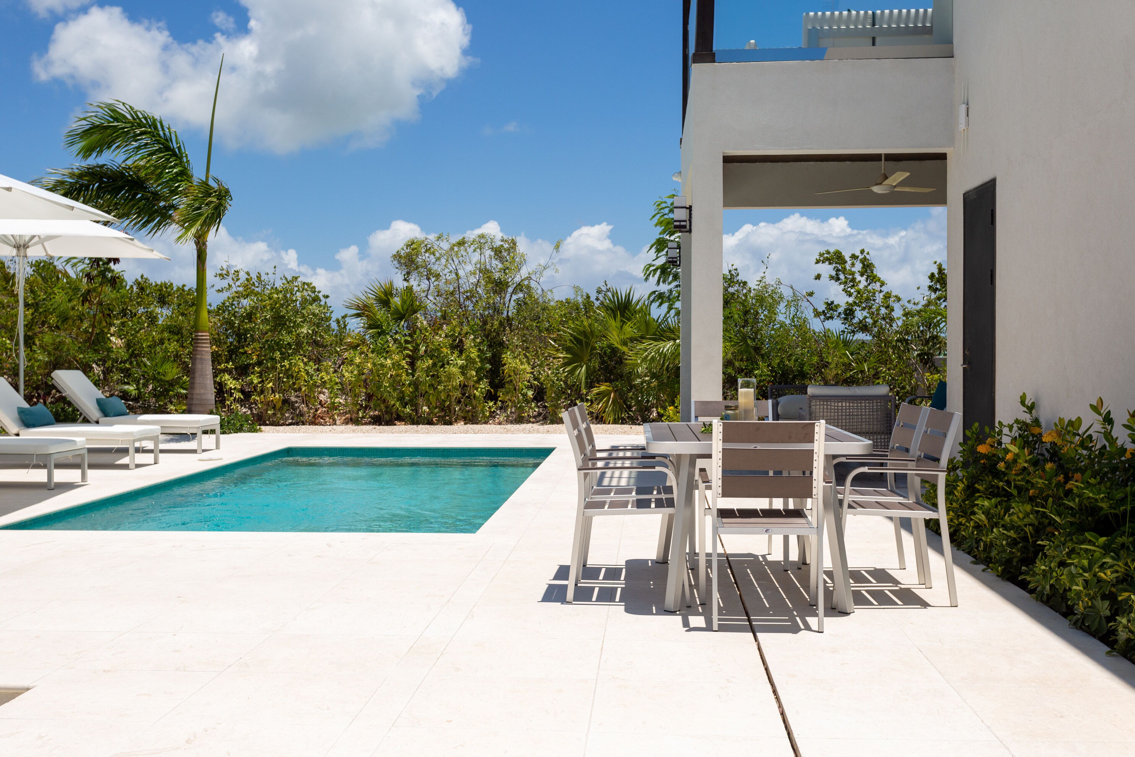 The pool and an outdoor dining table next to the covered terrace.