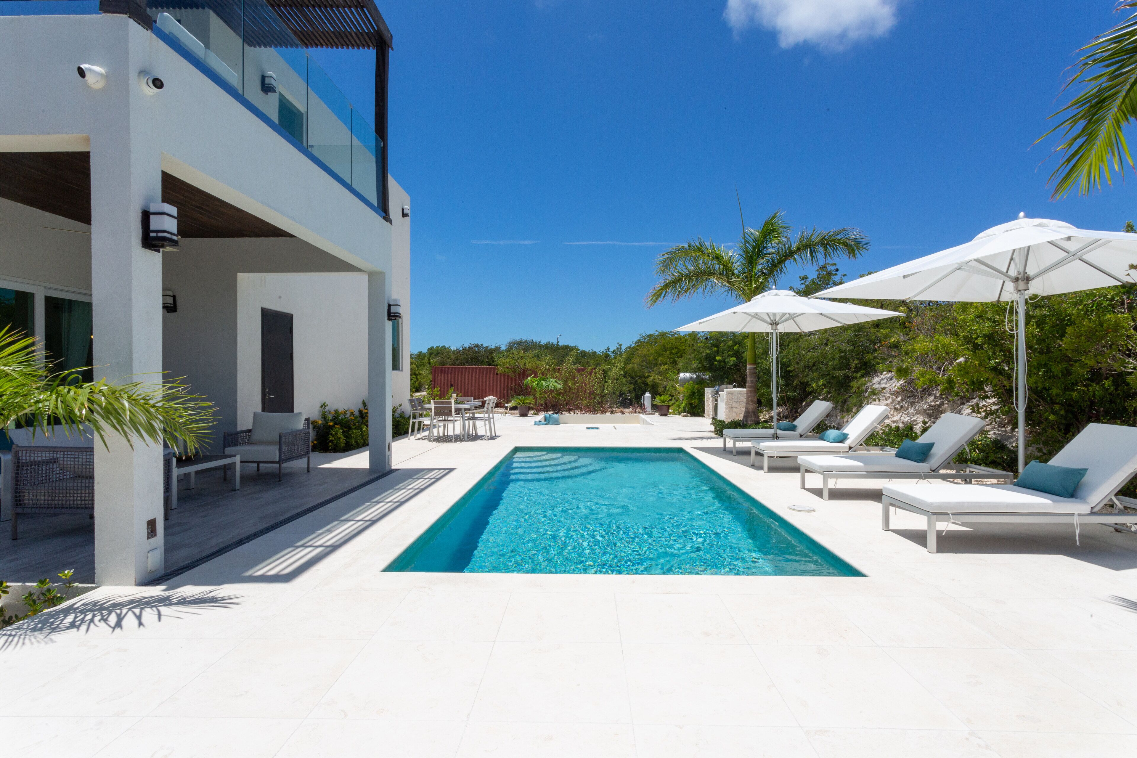 The pool with loungers, umbrellas, and the covered terrace of the villa.