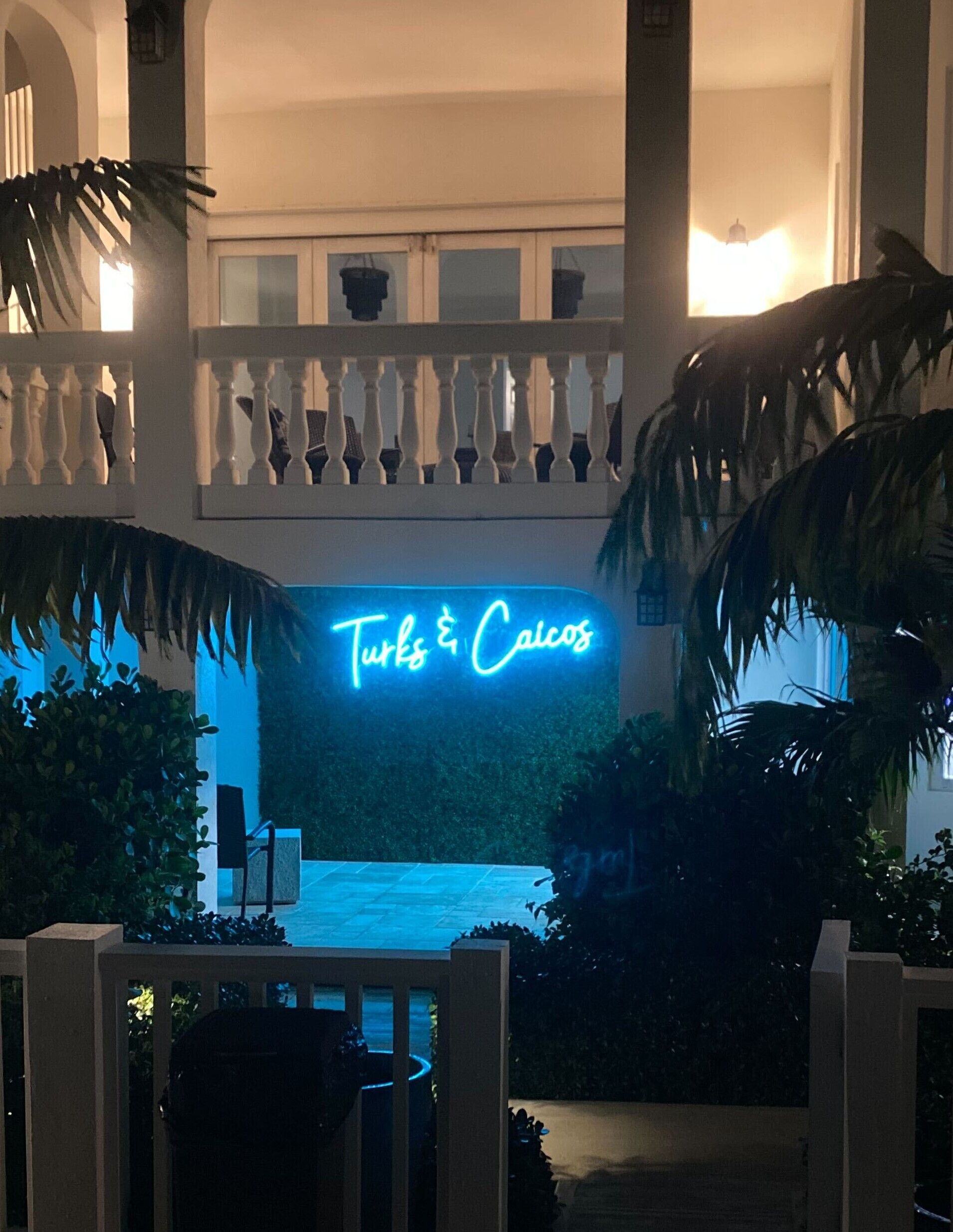 A courtyard at night, with a neon sign that reads Turks and Caicos.