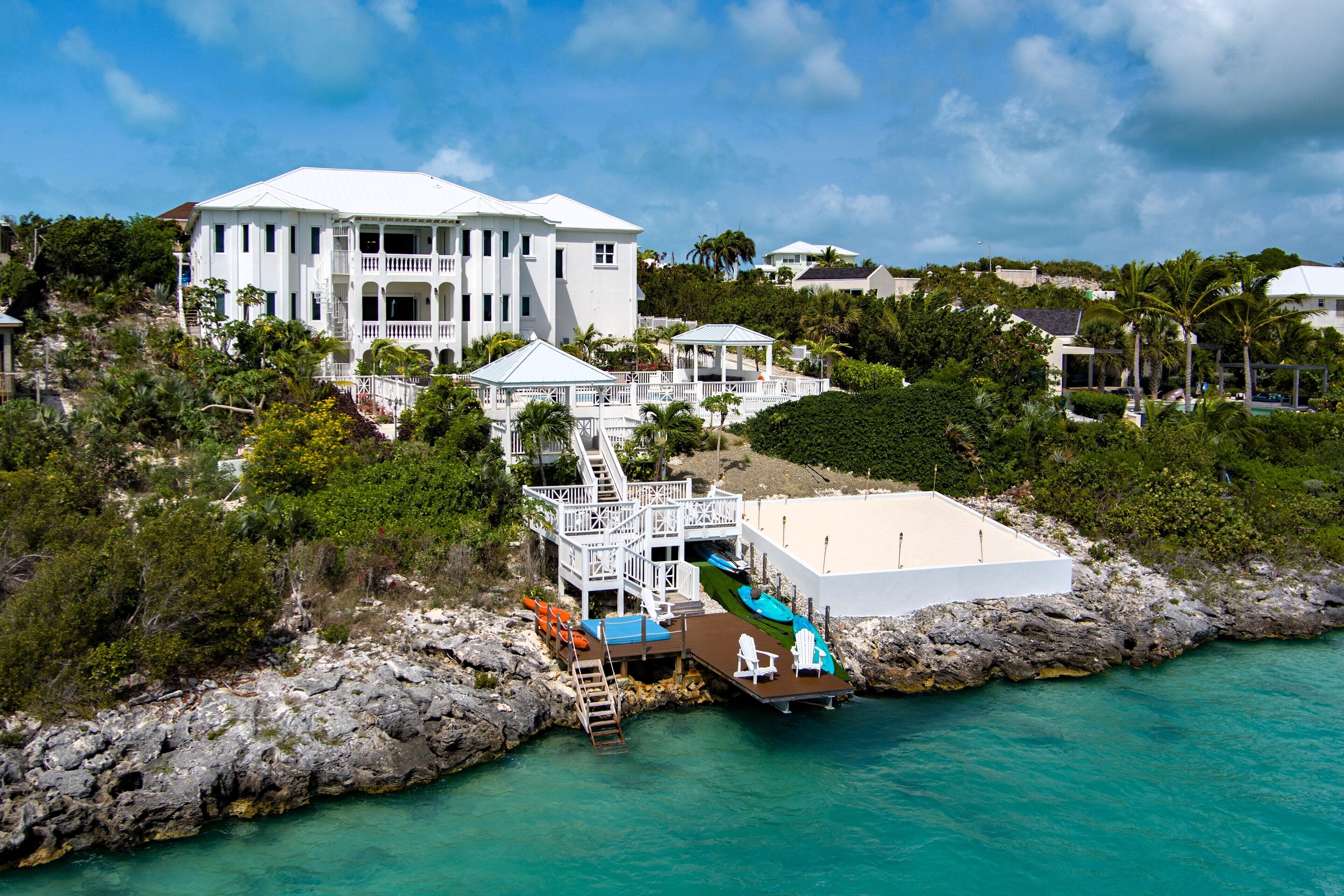 The villa above the shore, with a dock and kayaks.