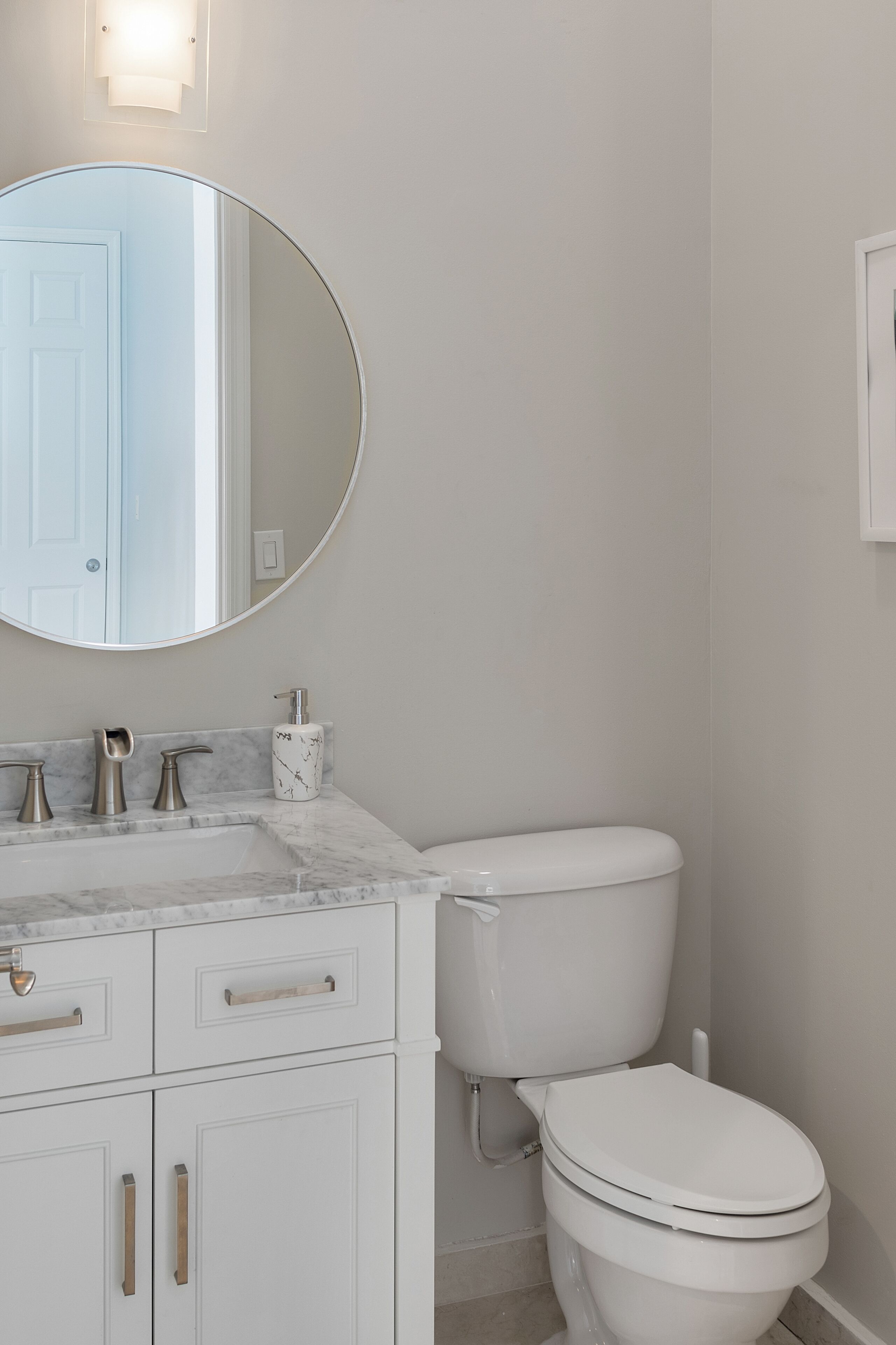 A bathroom with a vanity and a round mirror.