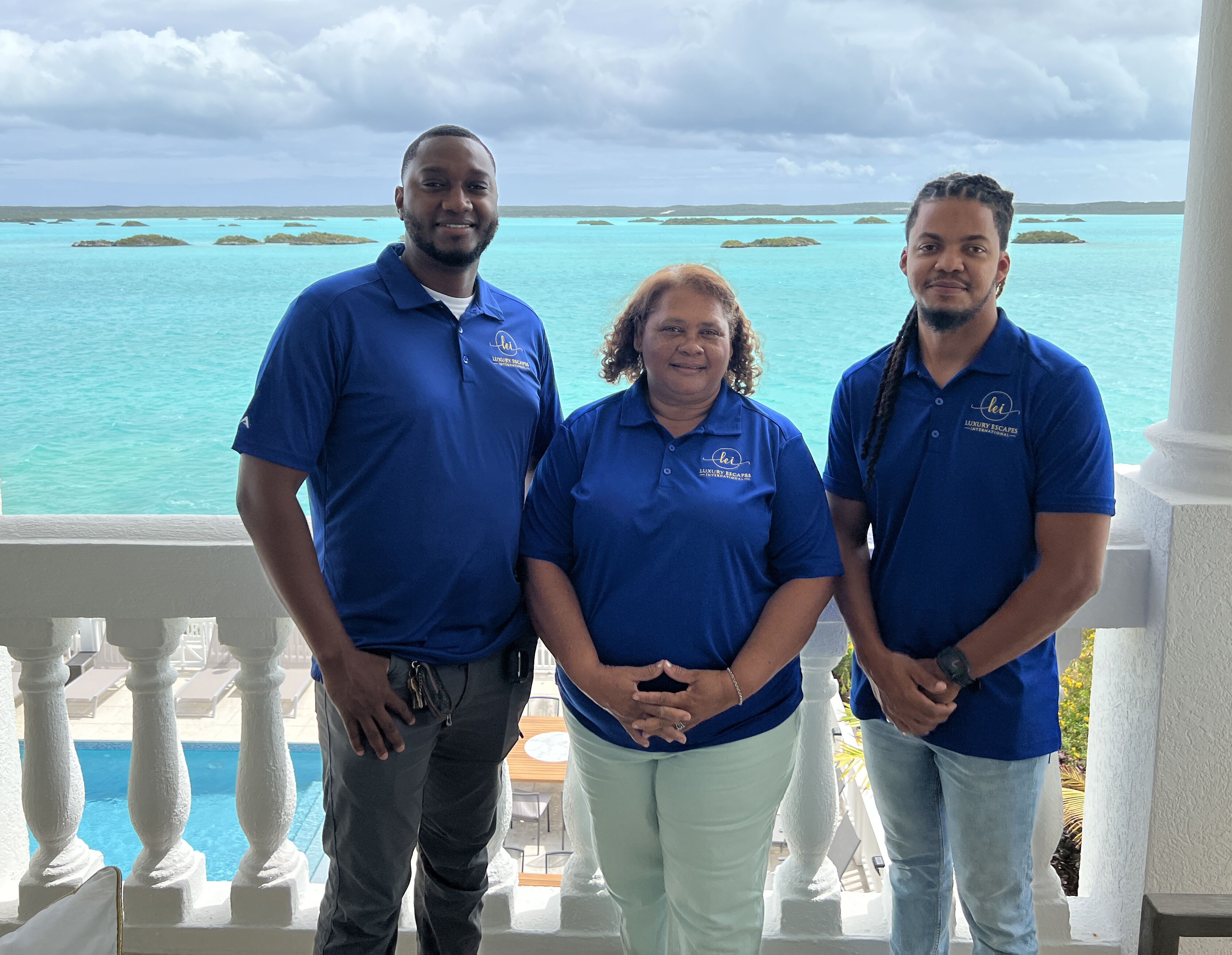 Three staff members on a balcony above the Chalk Sound lagoon.