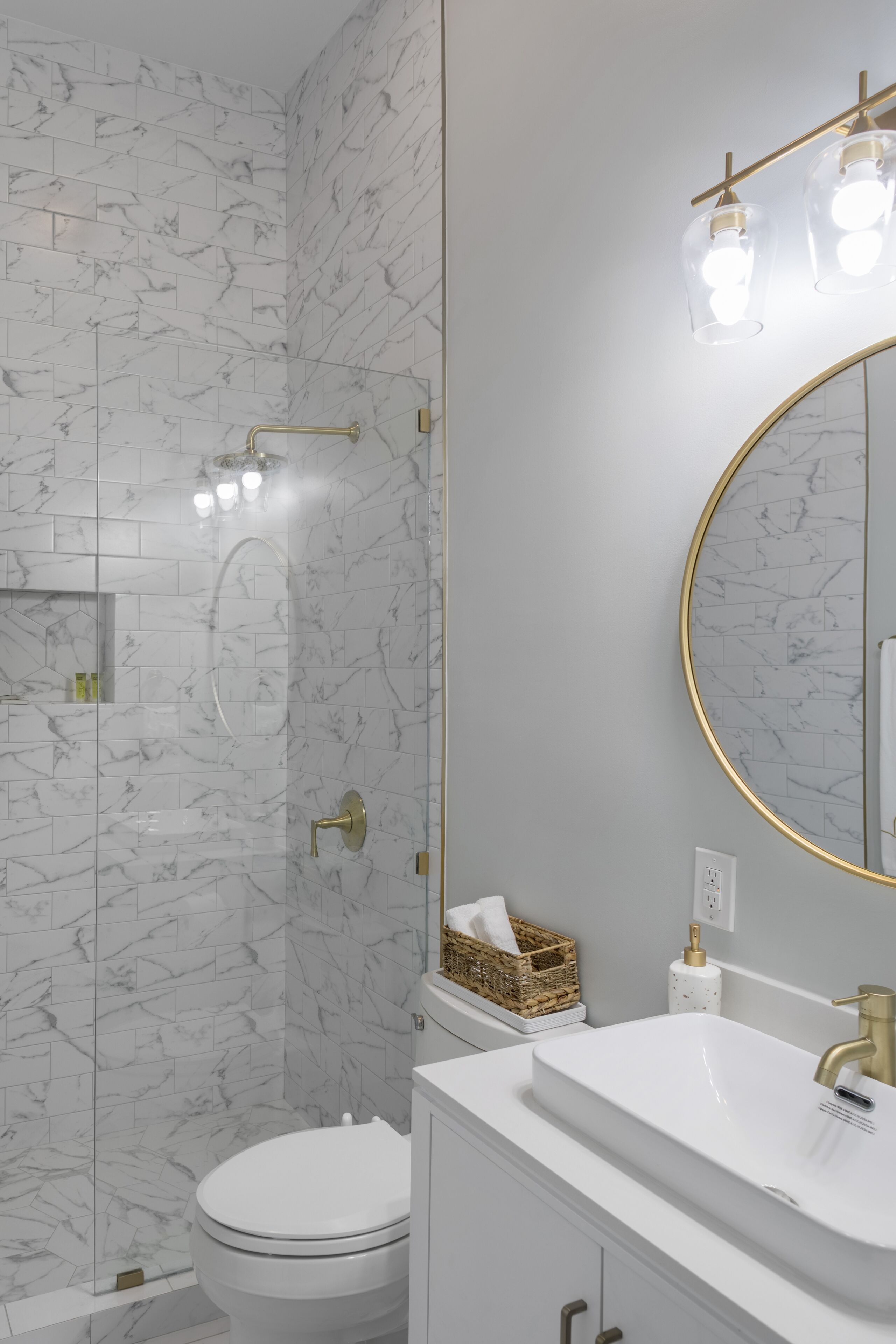 A bathroom with a walk-in shower and a round mirror.