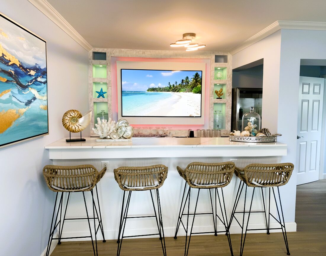A bar counter with four stools and a television.