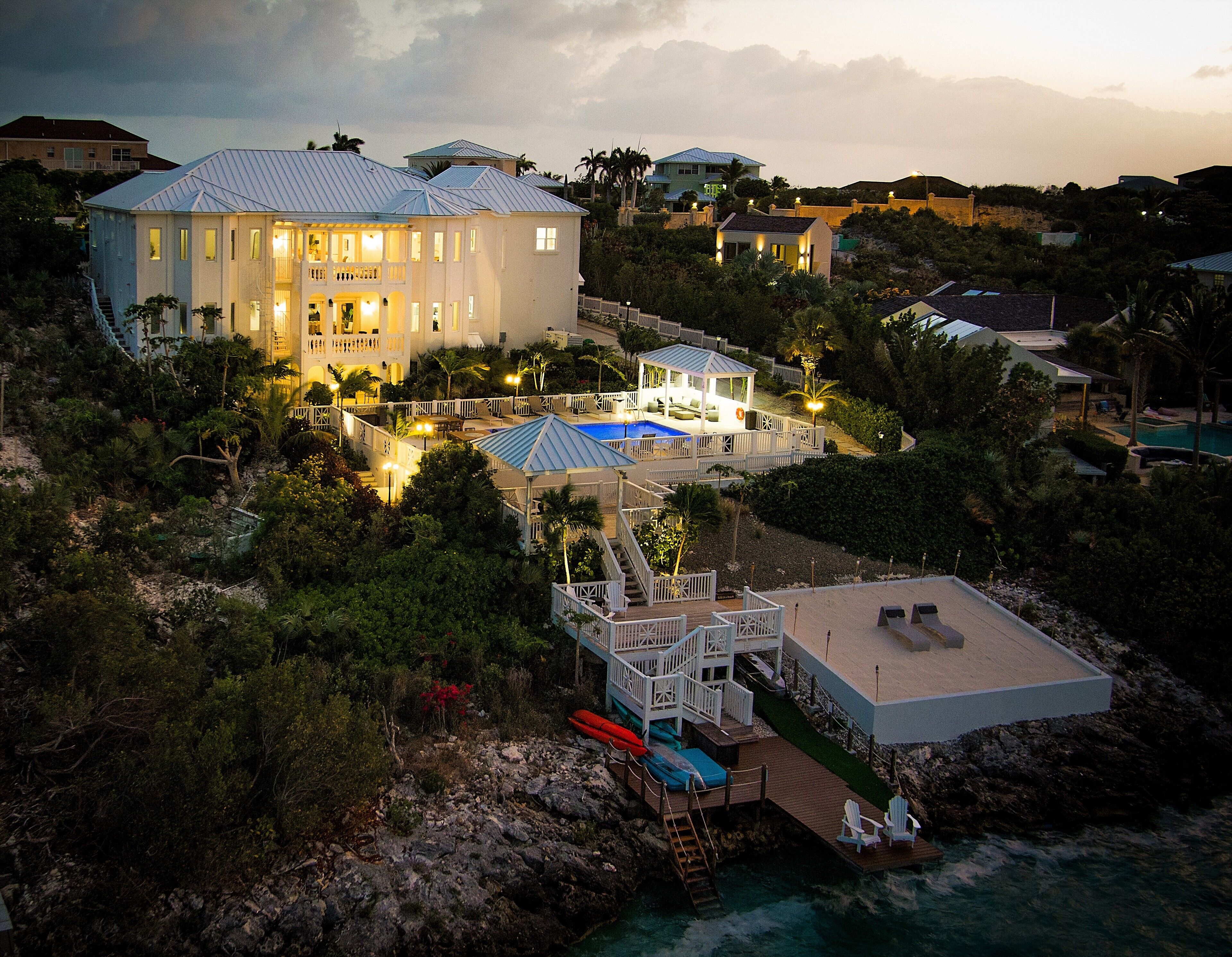 The villa at dusk, with the pool and the dock lit.
