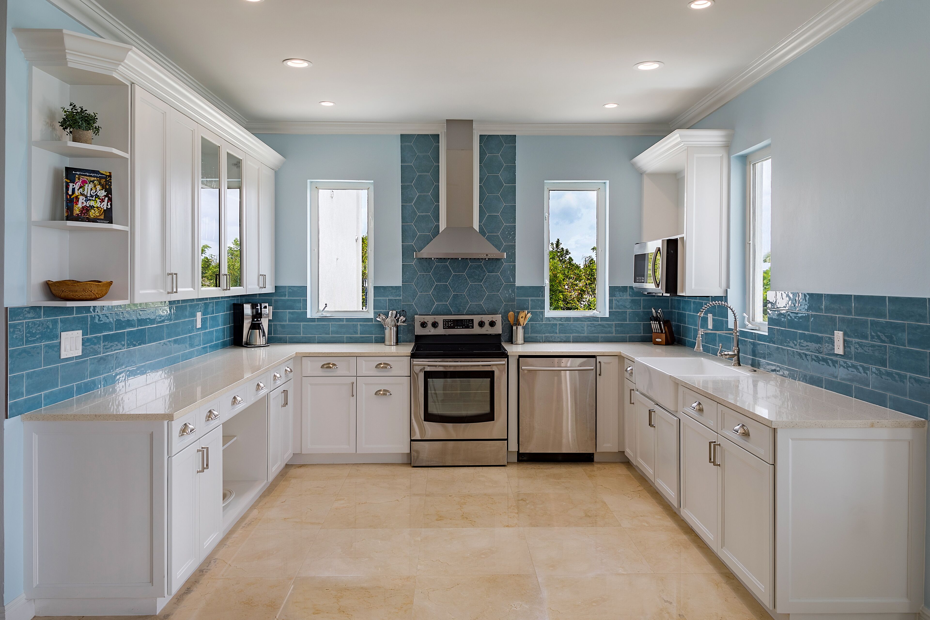 A kitchen with white cabinets and blue tile.
