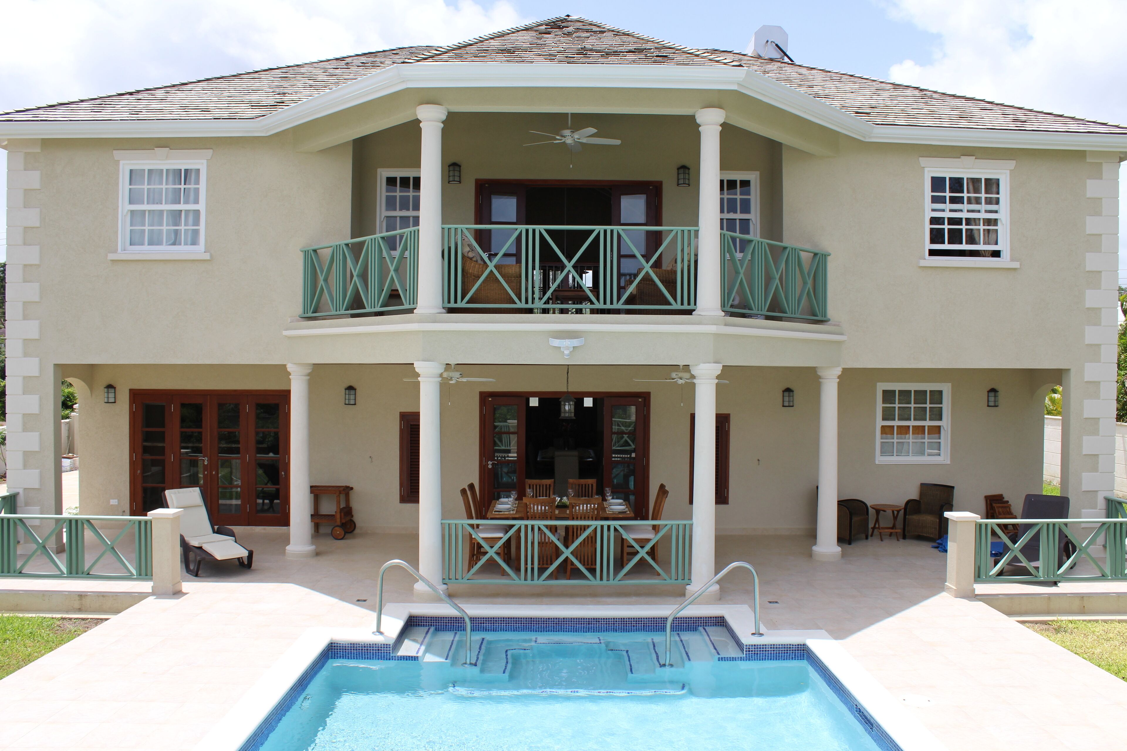 The rear of the villa, with the covered patio, the upper balcony, and the steps into the pool.