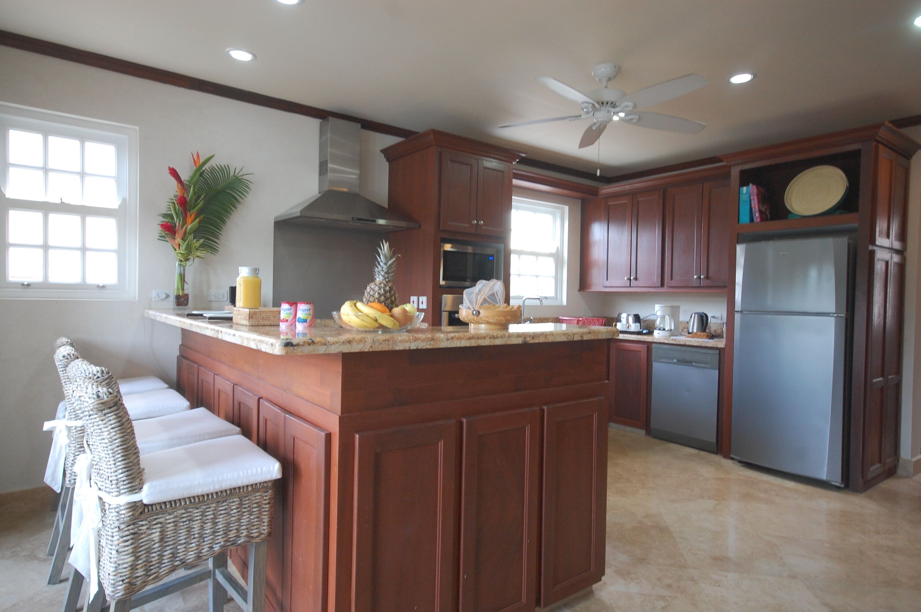 The kitchen, with wood cabinets, a granite breakfast bar, and wicker stools.