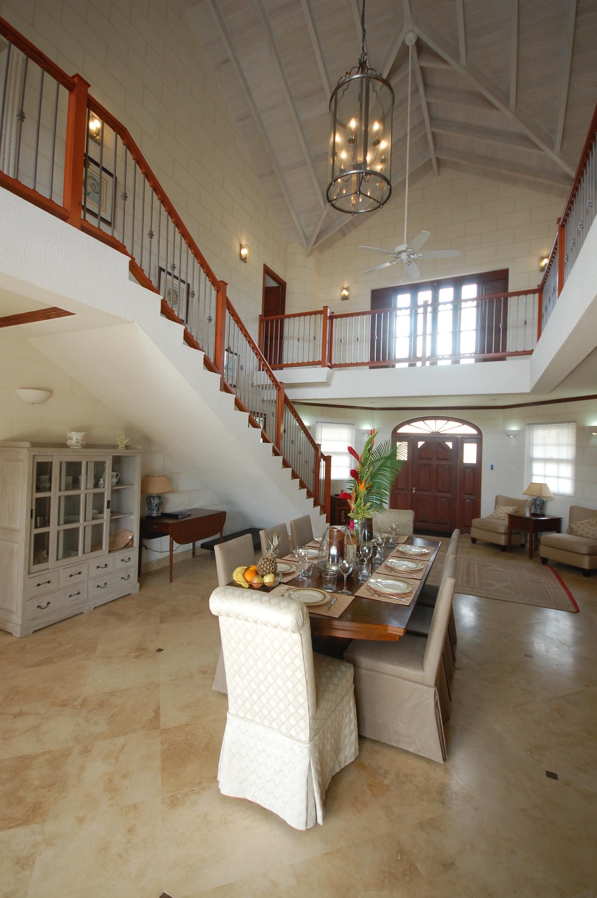 The two-story hall, with the staircase, the dining table, and the front door.