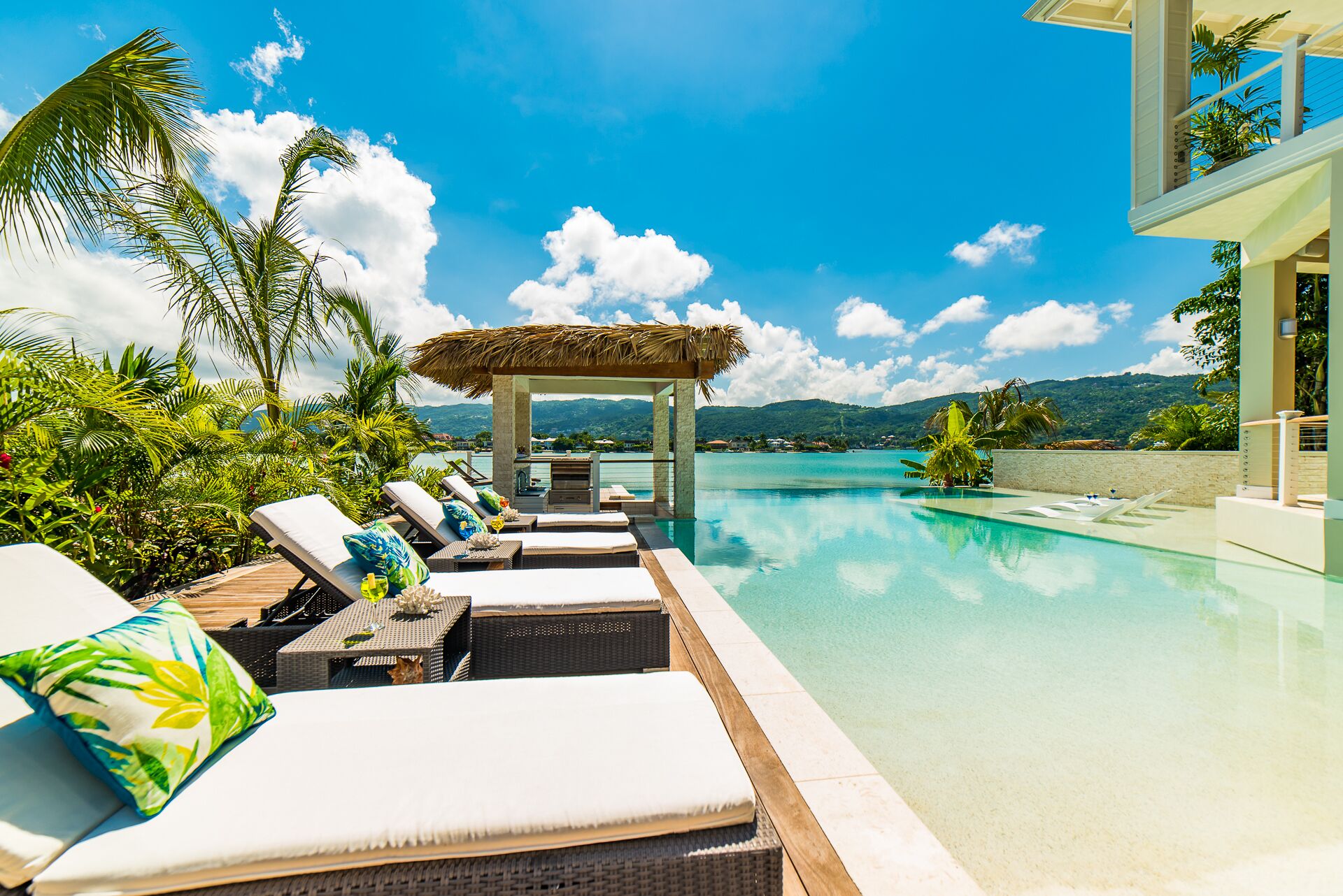 Loungers by the infinity pool with a view of the sea.