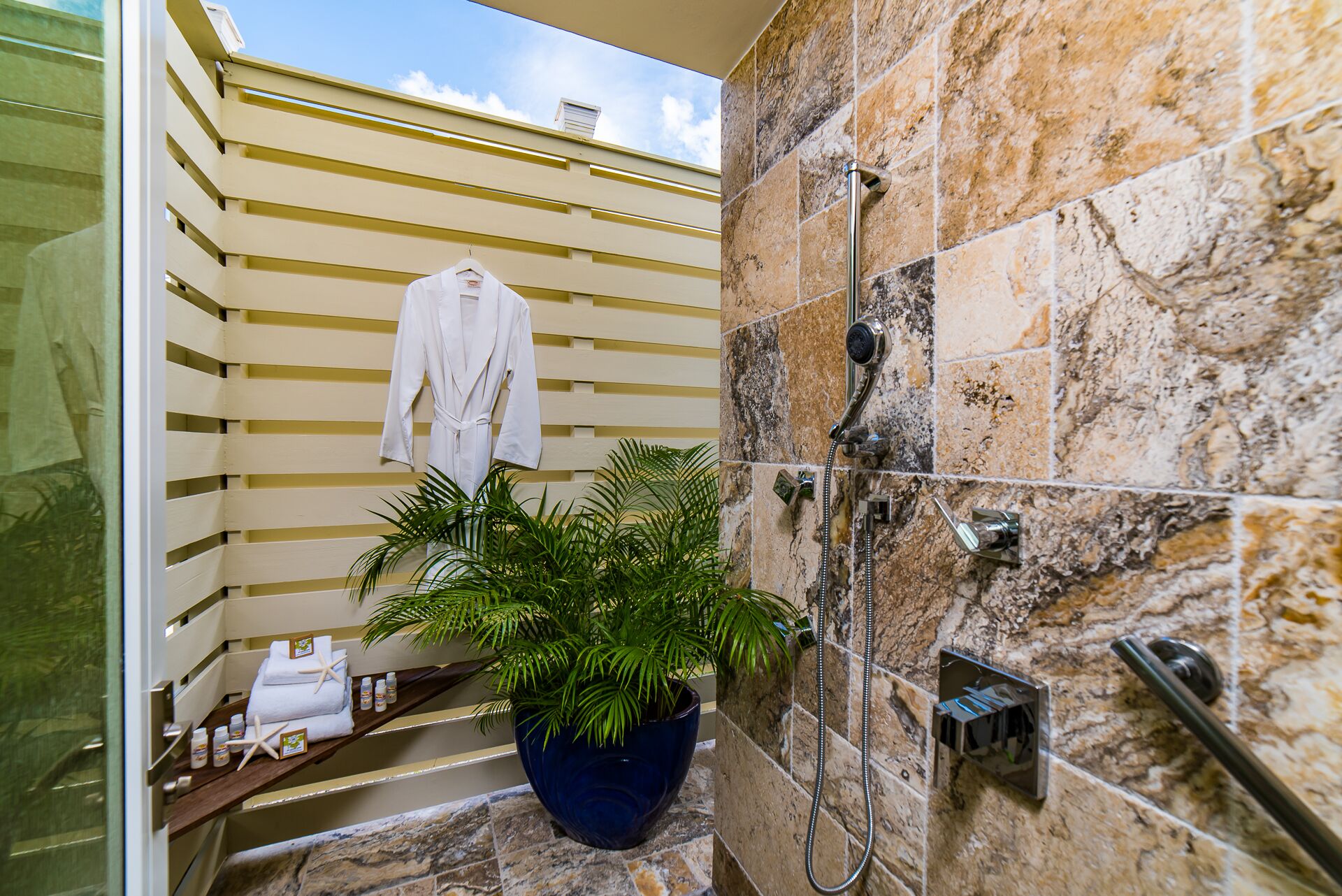 An outdoor shower with a stone wall and a robe.