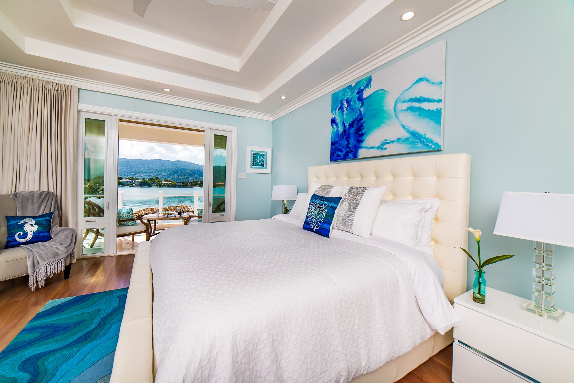 A bedroom with a king bed and a view of the sea.