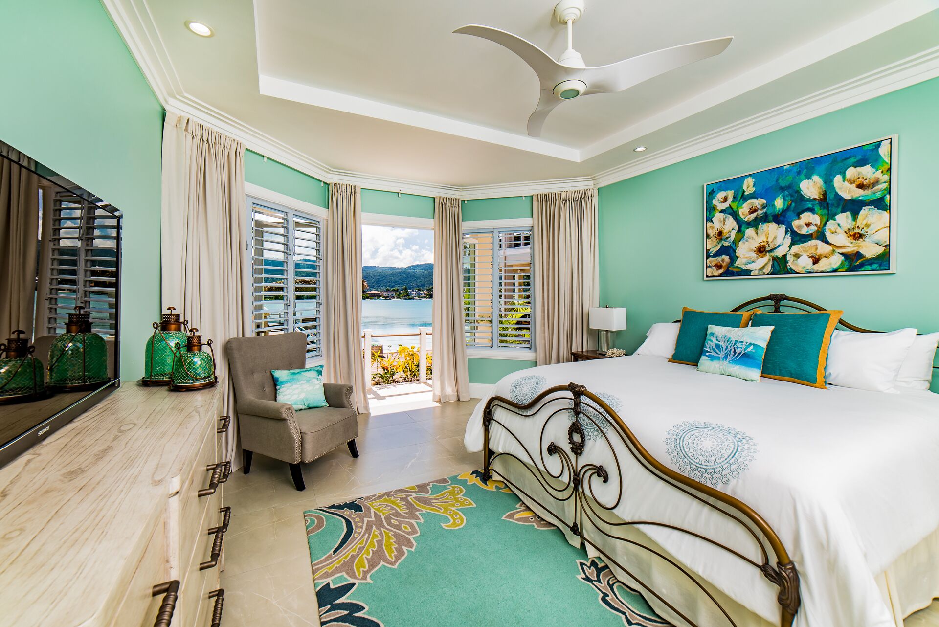 A bedroom with a metal bed frame and a view of the sea.