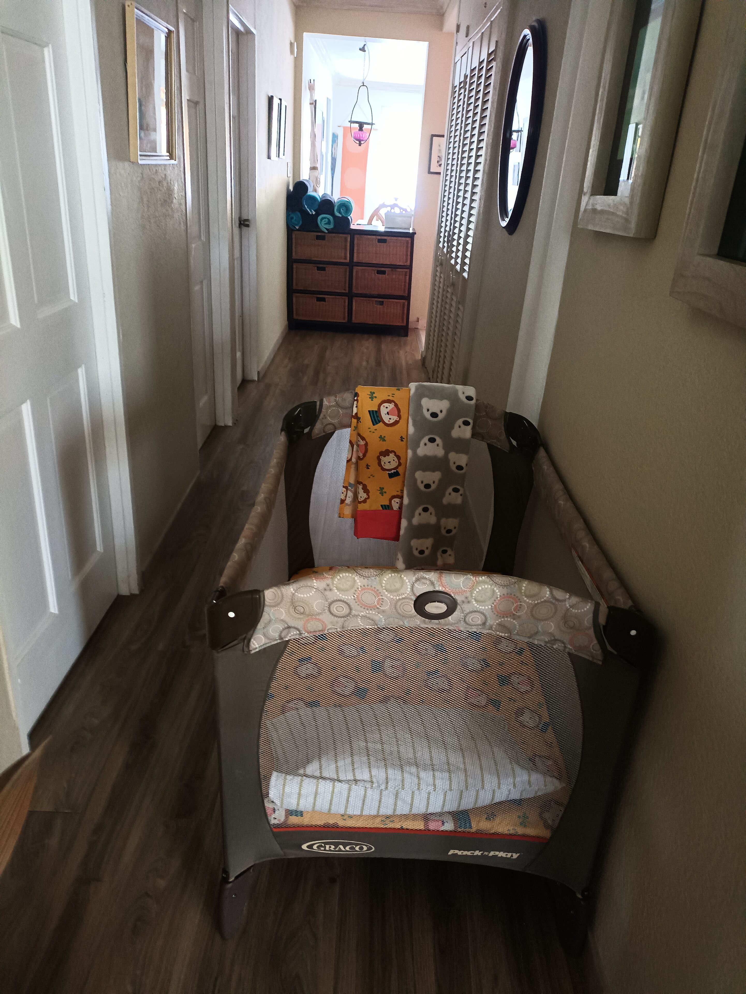 A hallway with a travel crib for a baby.