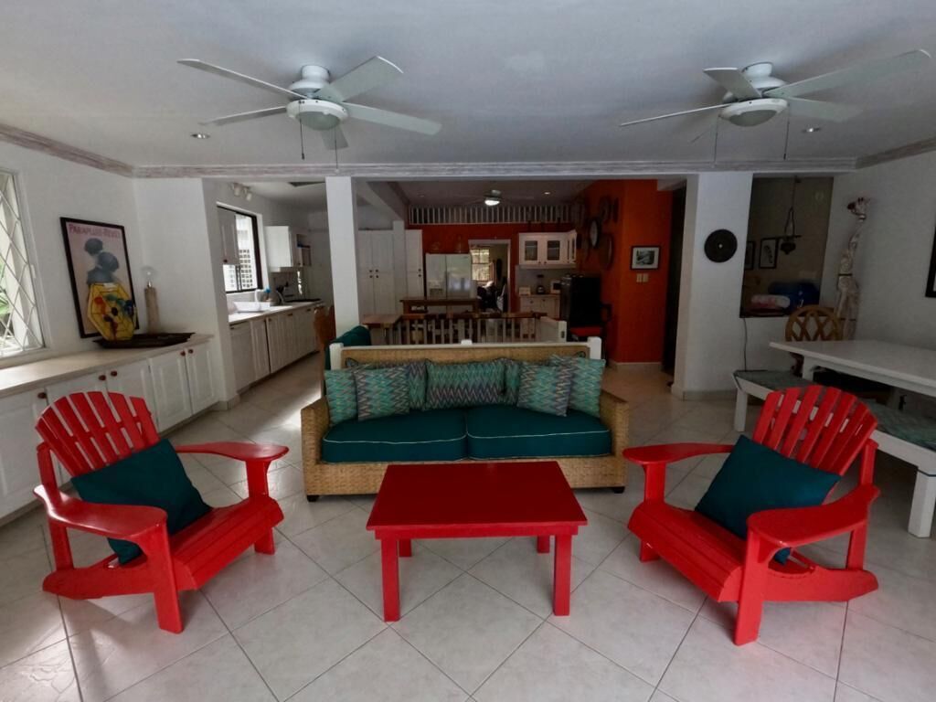 A living room with a wicker sofa and two red chairs.