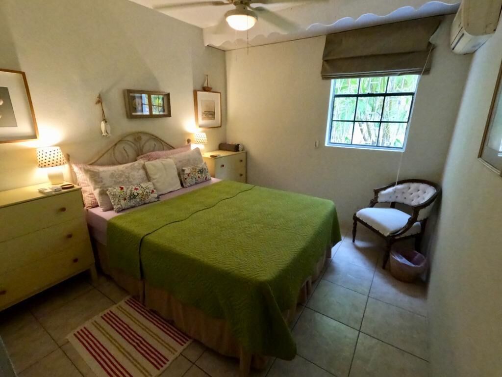 A bedroom with a double bed, two dressers, and an armchair.