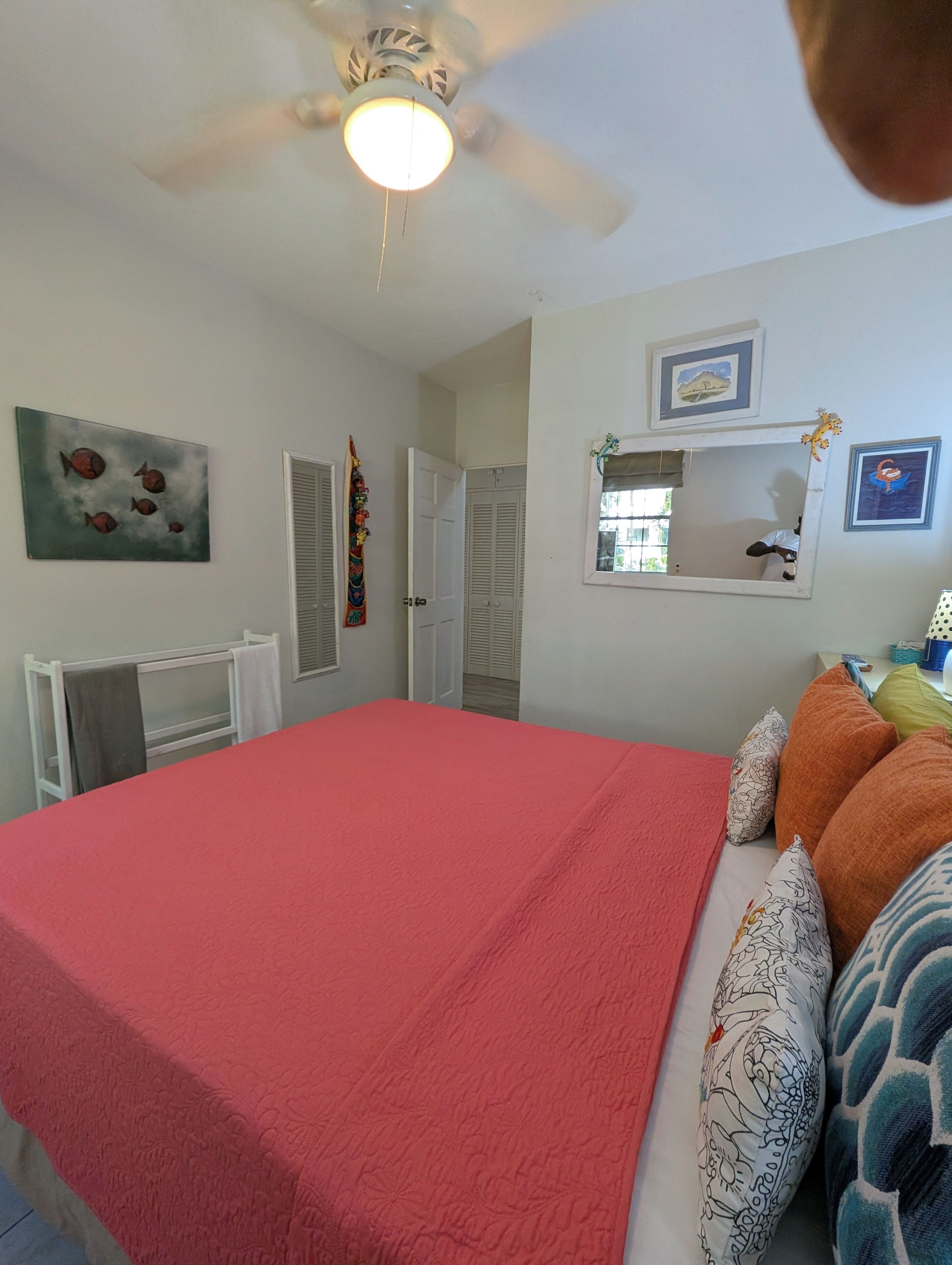 A bedroom with a pink bed cover and a wall mirror.