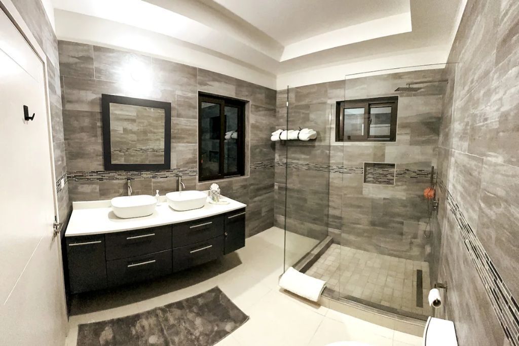 A bathroom with two sinks, a large mirror, and a glass shower.