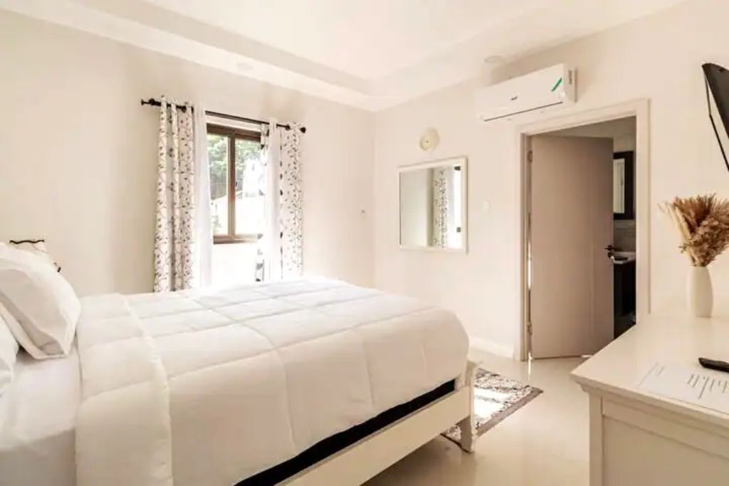 A bedroom with a double bed, a mirror, and a door to a bathroom.