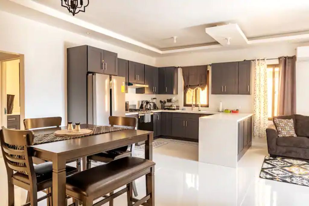 An open kitchen with dark cabinets, a refrigerator, and a dining table.