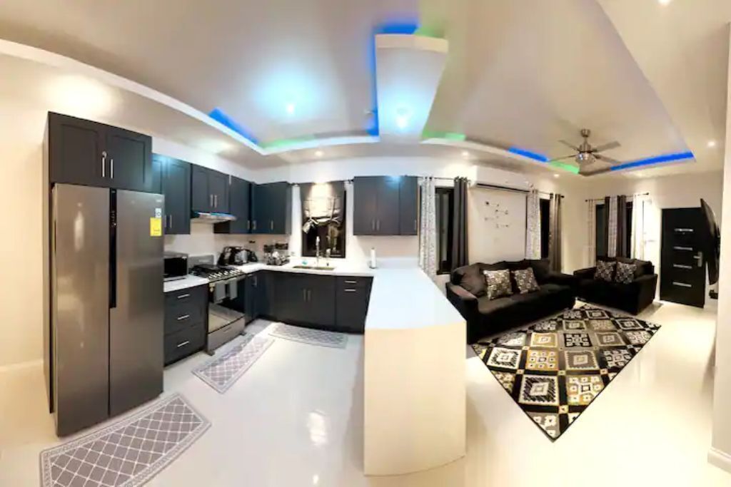 An open room with a kitchen, a white counter, and two dark sofas.