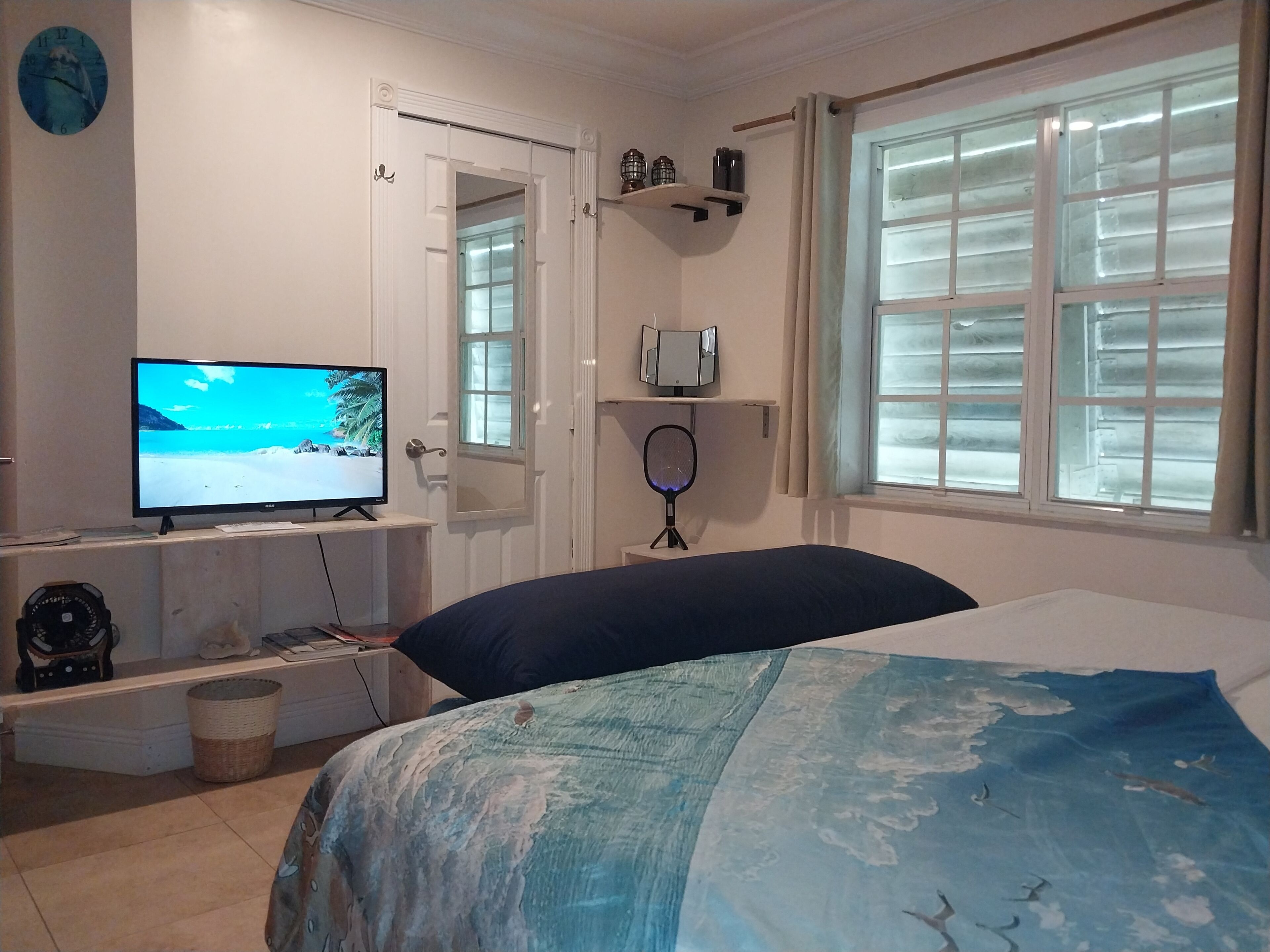 A bedroom with a bed, a television, and a window.