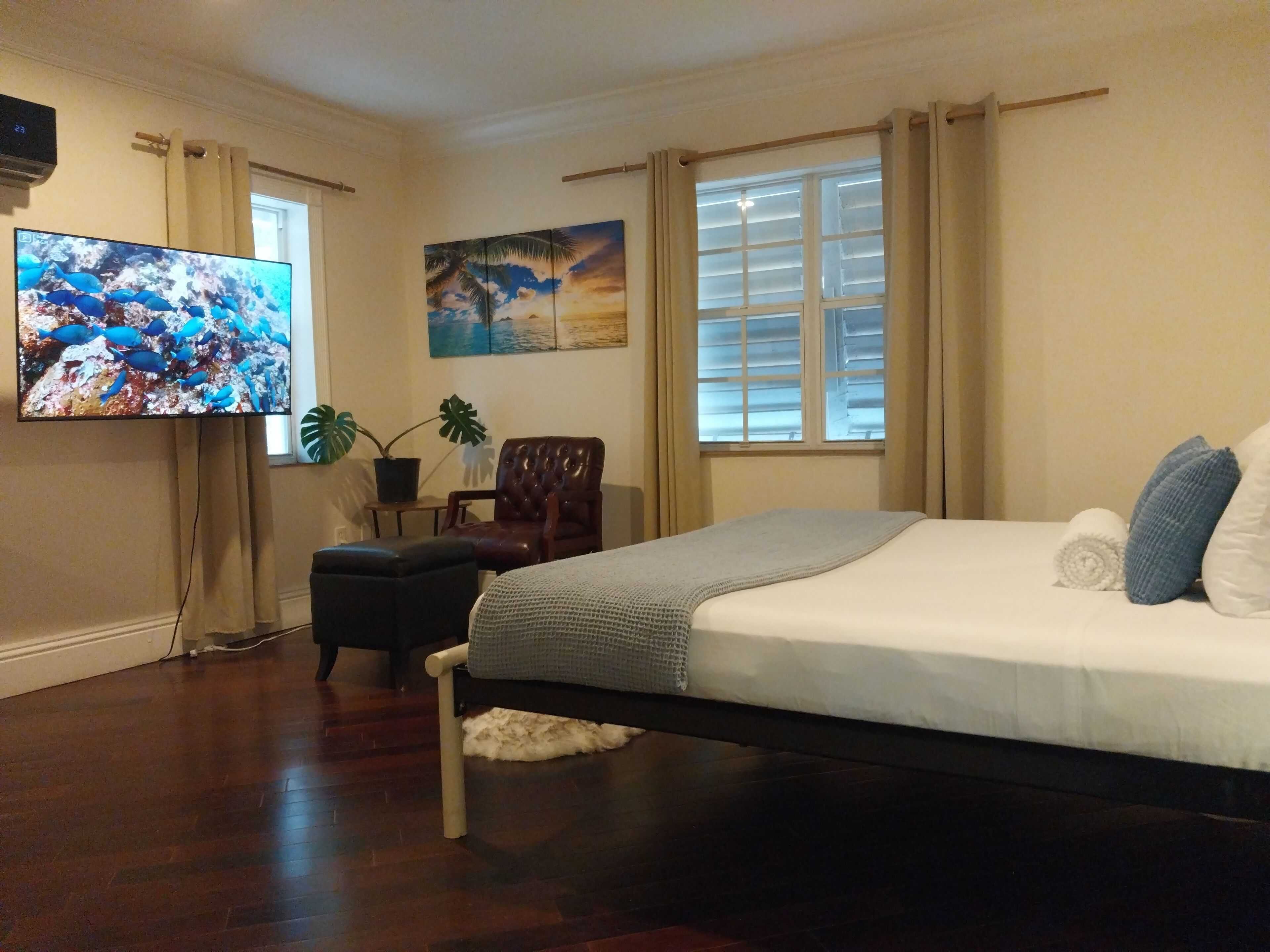 A bedroom with a bed, a television, and a chair.