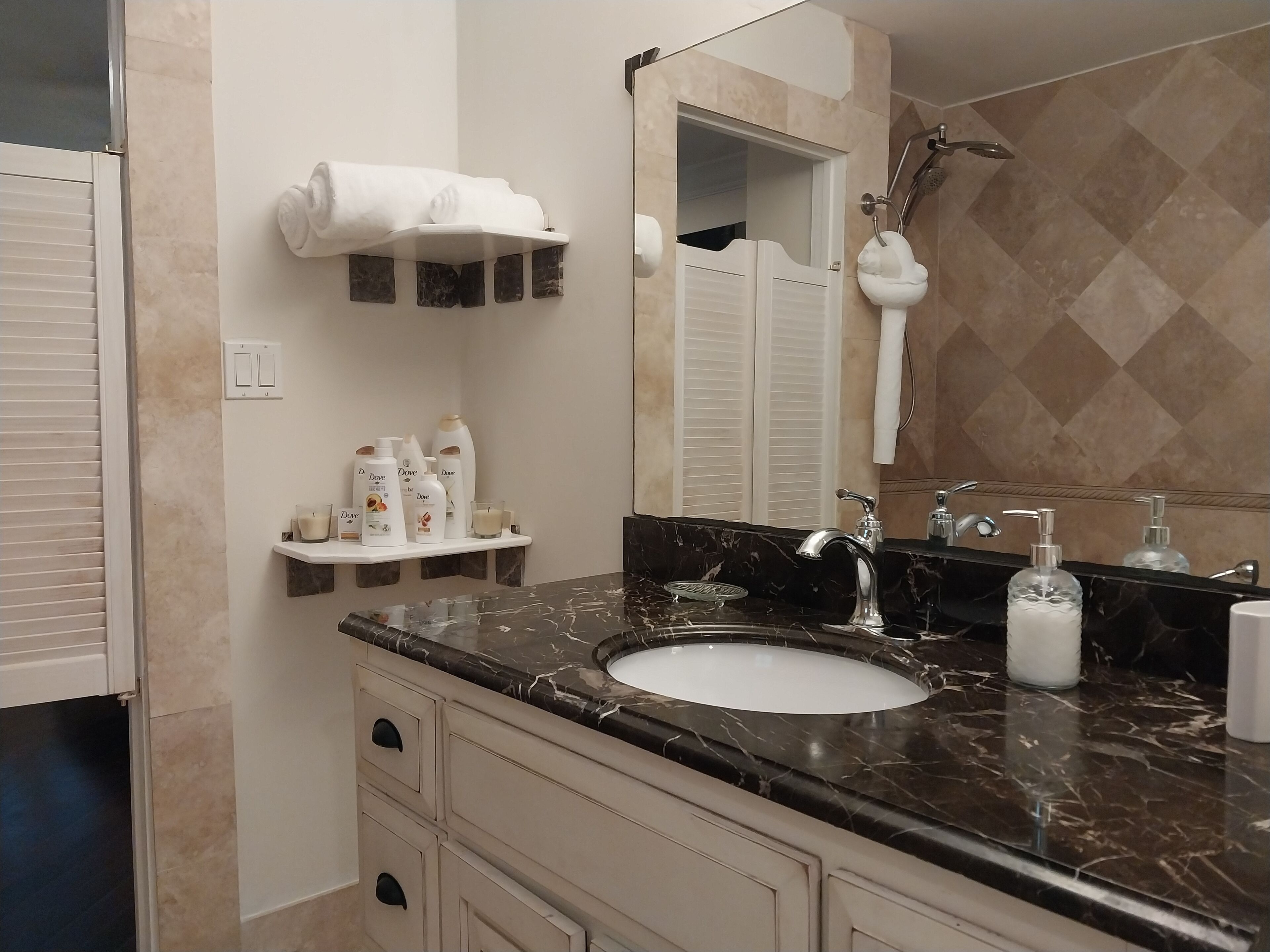 A bathroom with a dark stone counter and a shower.